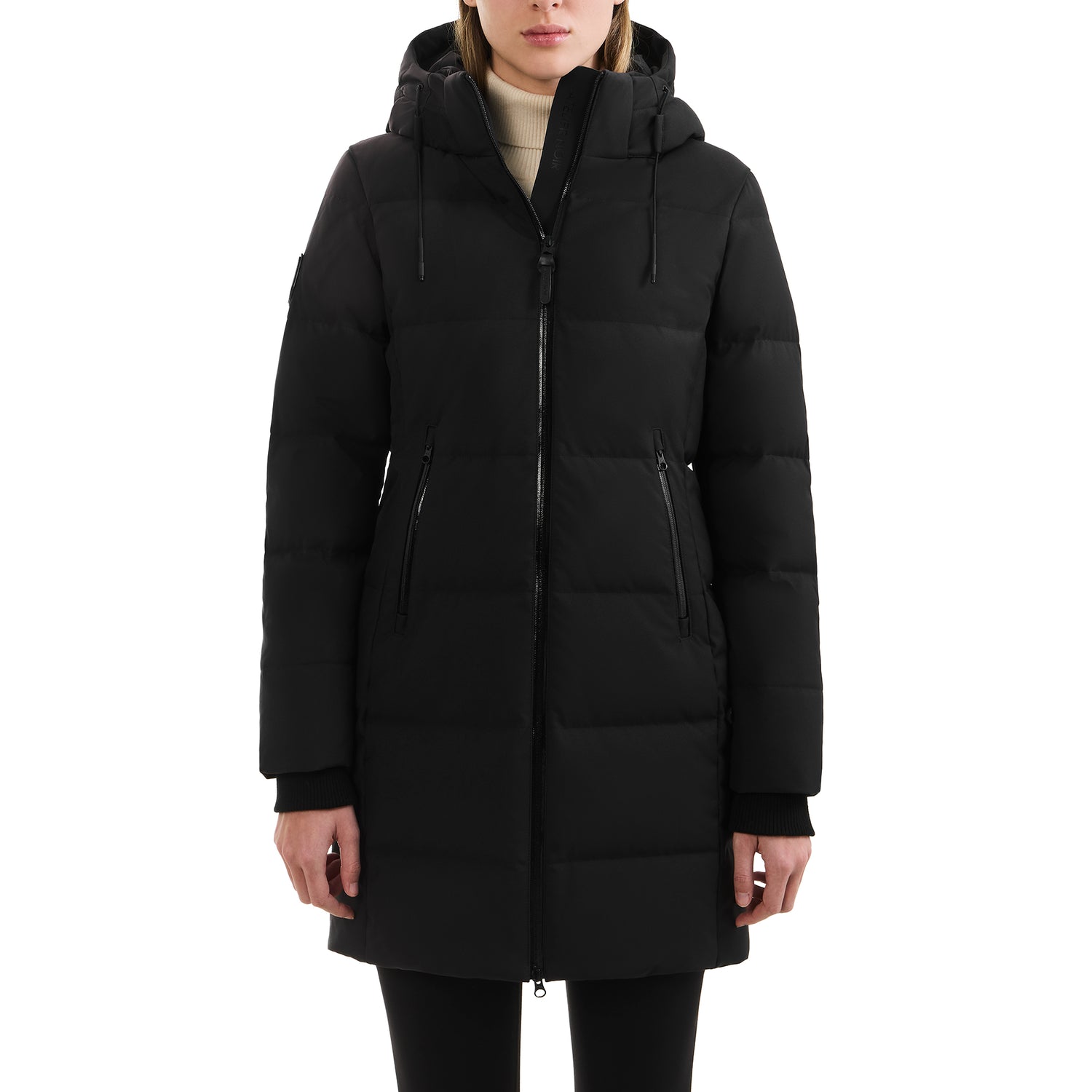A person wears the Rudsak SYDNEY COM - 4123511 Black long water-repellent puffer coat with a hood, front zipper, and two zippered pockets, standing face forward against a white background with hands relaxed at their sides.
