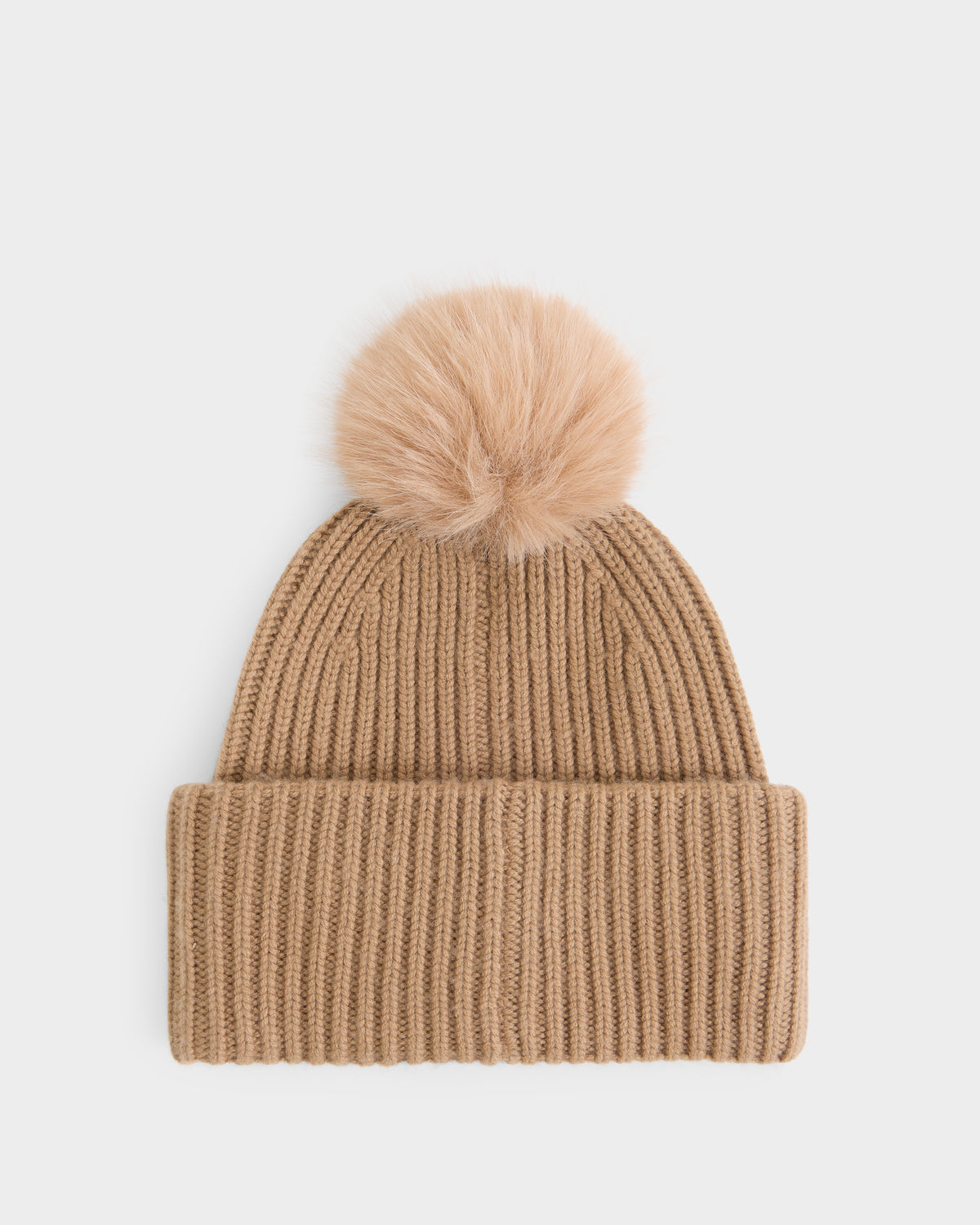 A true cold-weather essential, the DARA - 8425019 Camel by Rudsak is a tan knit women’s cashmere tuque featuring a wide folded brim and a fluffy faux fur pom pom on top, displayed against a plain white background.