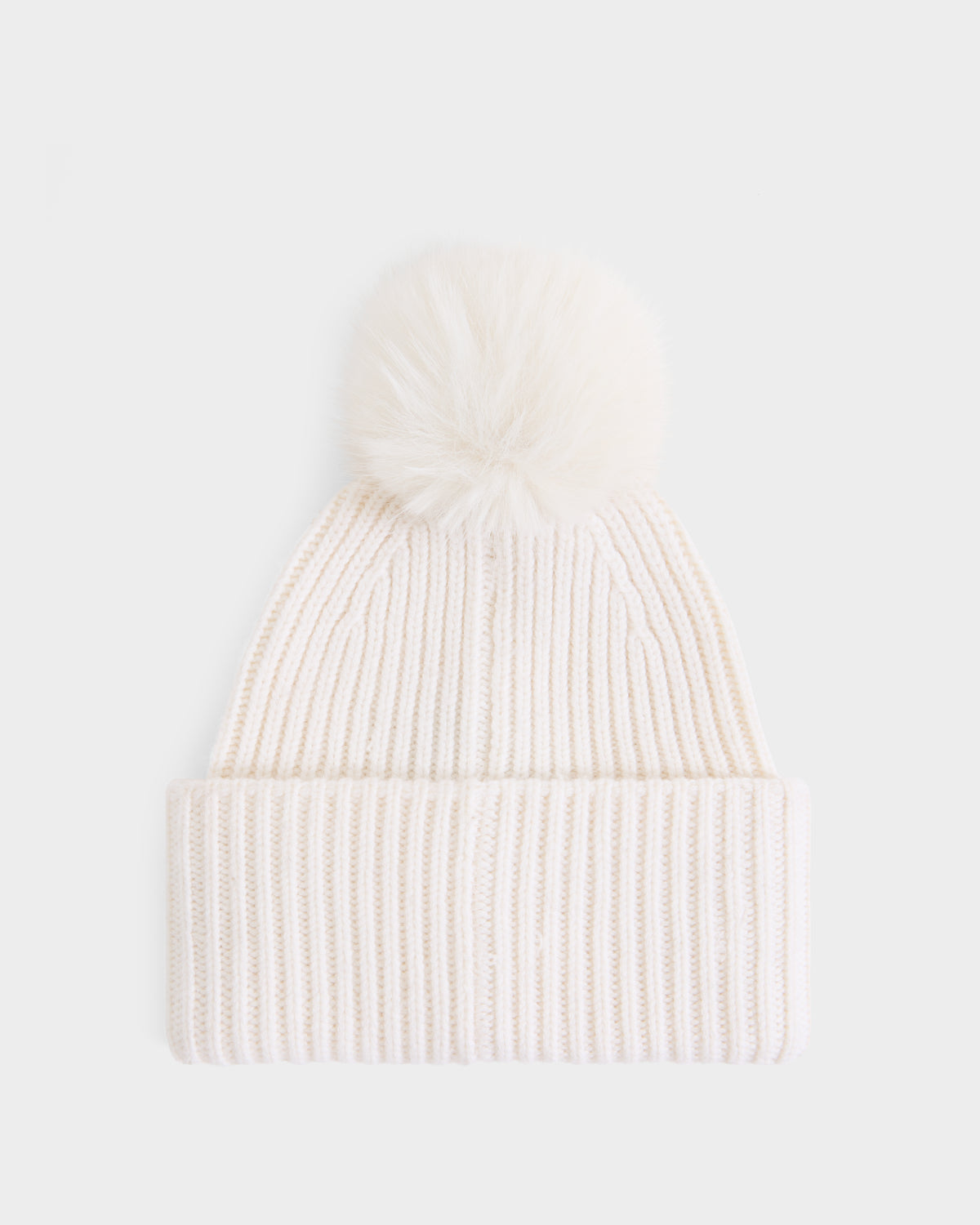 The DARA - 8425019 Vanilla by Rudsak is a women’s white ribbed knit tuque featuring a folded brim and a large, fluffy faux fur pom pom on top. Crafted from a soft cashmere wool blend, it is shown against a plain white background.