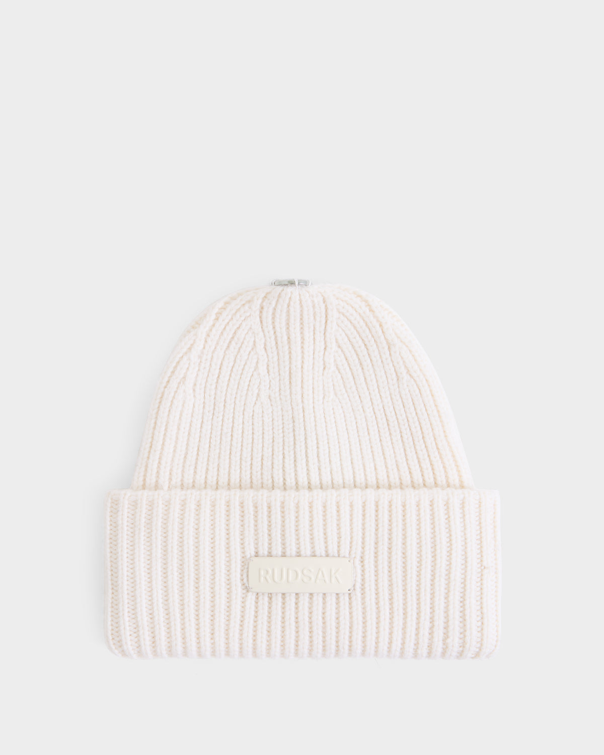 A women’s tuque named DARA - 8425019 Vanilla by Rudsak, crafted from a soft cashmere wool blend in a cream hue, features ribbed knitting, a folded brim, and a rectangular front patch displaying the Rudsak brand name. The tuque is presented against a plain white background.