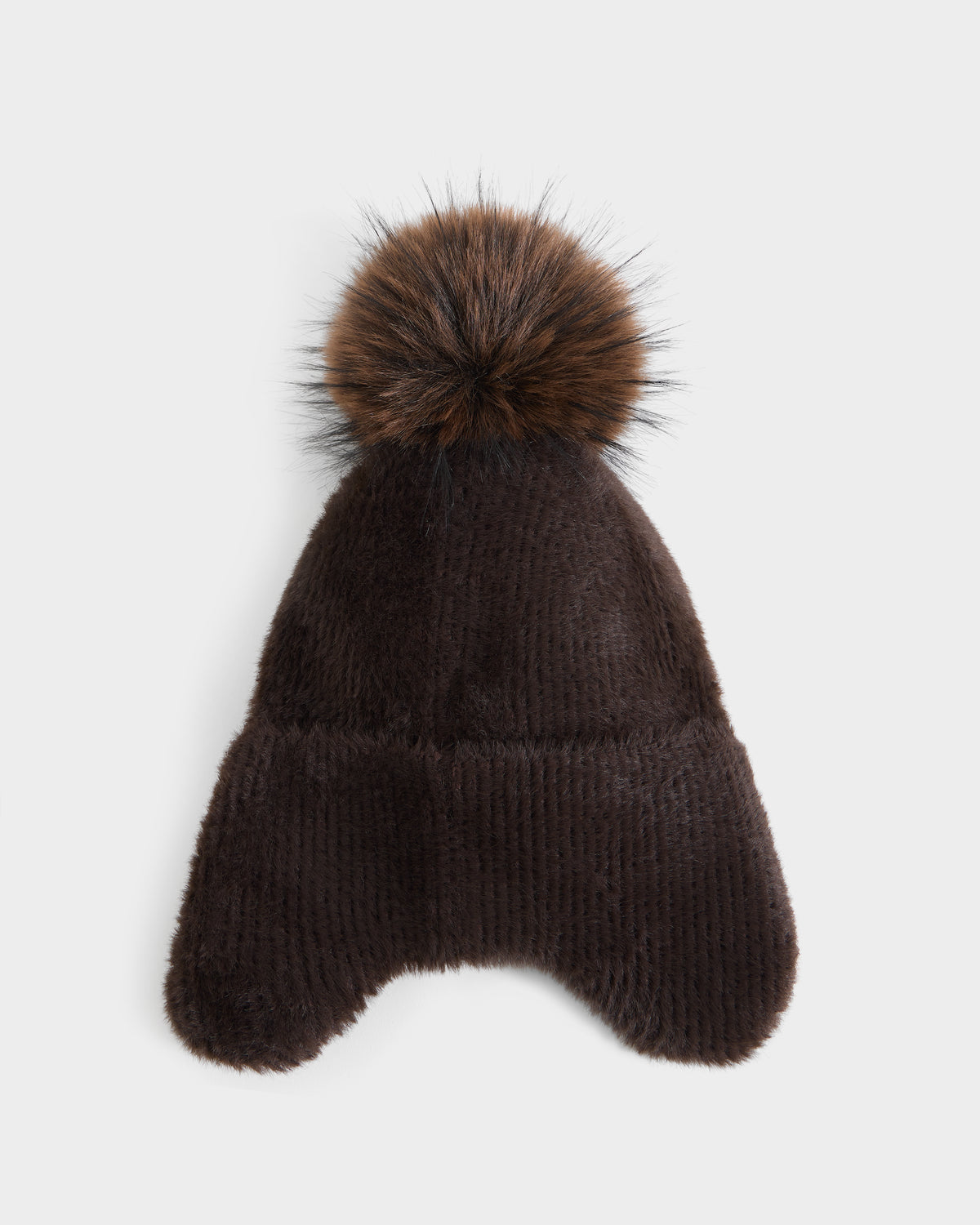 The Rudsak ICE - 8426519 Espresso is a dark brown, furry winter hat featuring two ear flaps and a large, fluffy pom-pom on top, displayed on a white background.