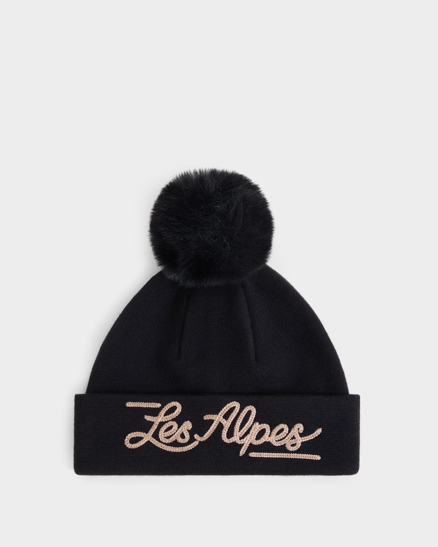 The Rudsak ESTELLA - 8426521 Black is a black knit beanie featuring a large pom-pom on top and “Les Alpes” embroidered in cursive beige letters on the folded brim, displayed against a plain white background.