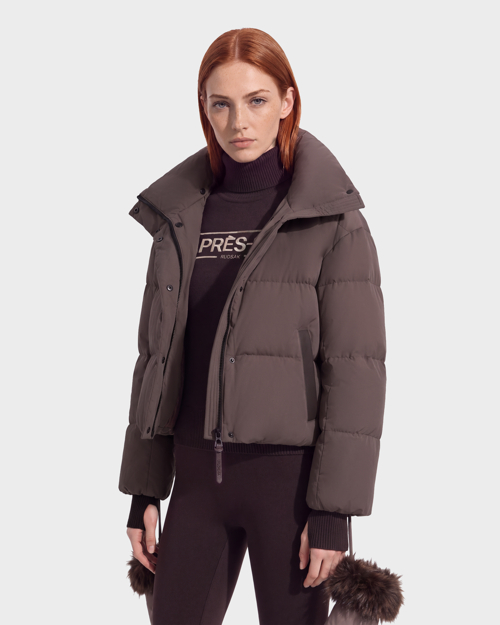 A person wearing an ALONDRA - 8126992 Espresso dark brown cropped puffer jacket with a high collar over a matching turtleneck sweater and leggings, styled as versatile winter outerwear.