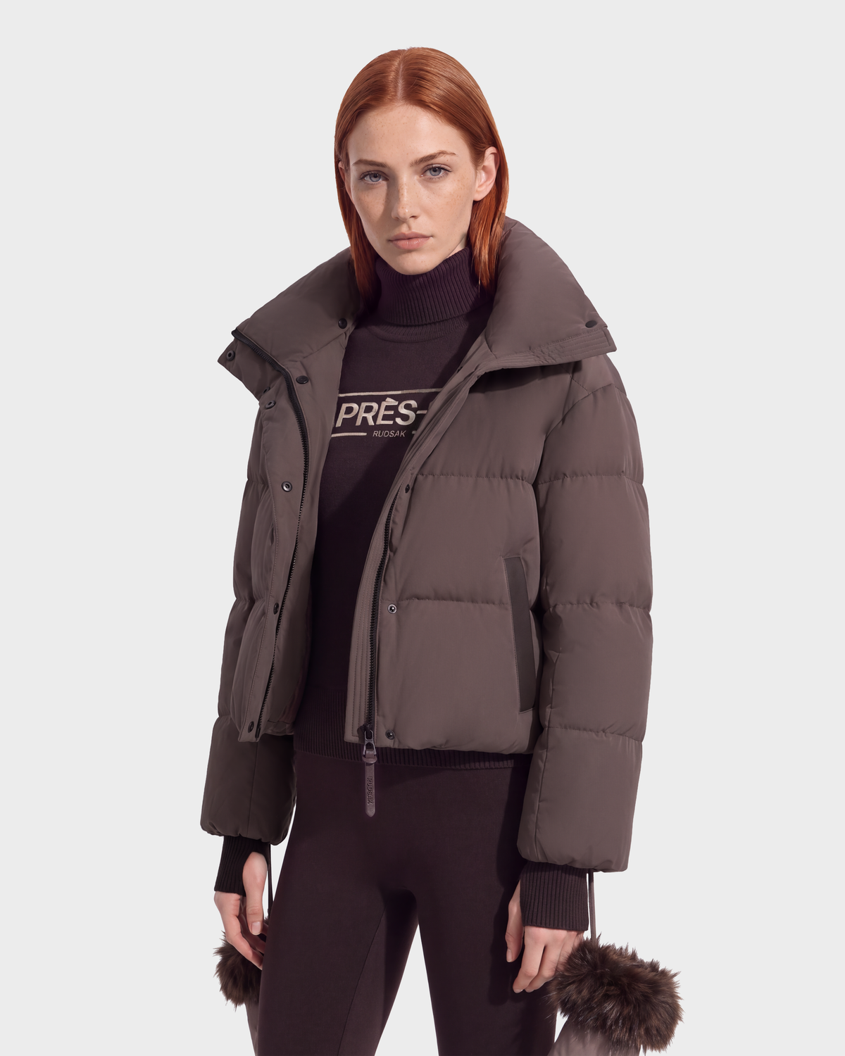 A person wearing an ALONDRA - 8126992 Espresso dark brown cropped puffer jacket with a high collar over a matching turtleneck sweater and leggings, styled as versatile winter outerwear.