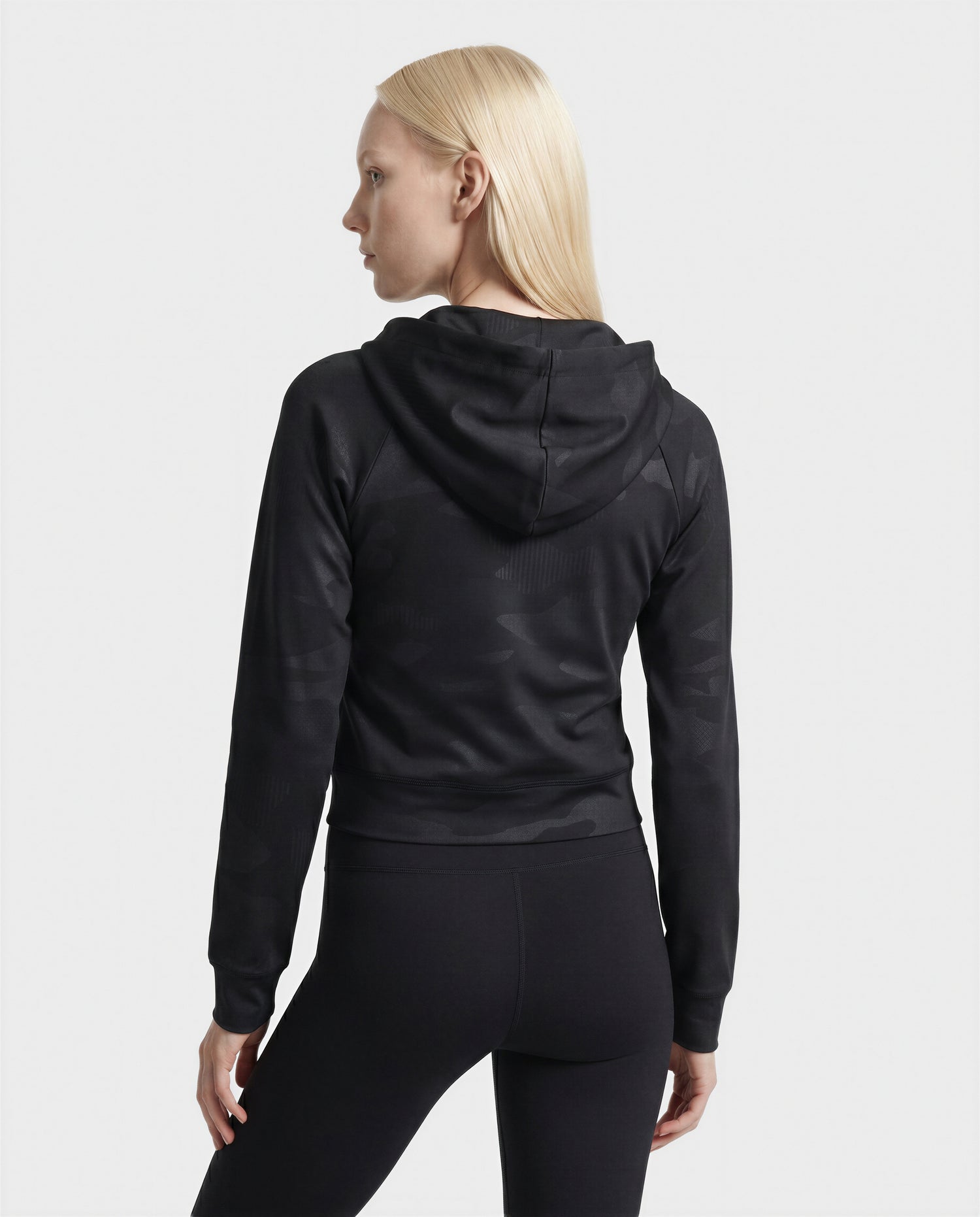 A person with long, straight blonde hair is seen from the back wearing the Rudsak SAMMY - L523014T Camouflage Black top, paired with black leggings against a plain white background for a casually luxurious look.