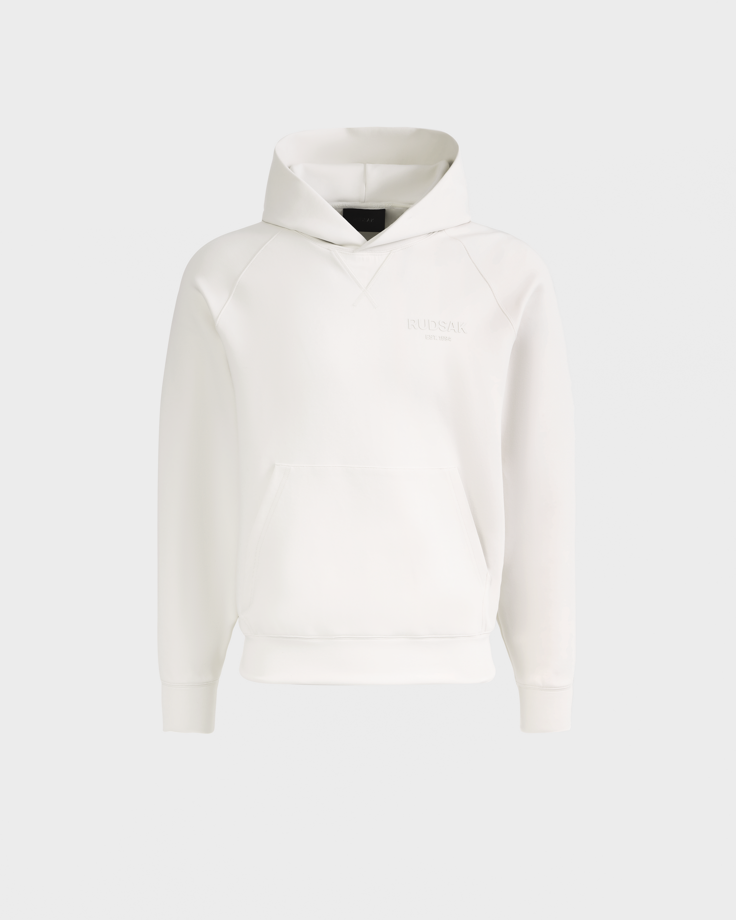 The Rudsak BARRY - 9524011 Vanilla W is a plain white unisex hoodie featuring long sleeves, a front kangaroo pocket, ribbed cuffs and hem, and subtle embossed chest text, shown on a light grey background.