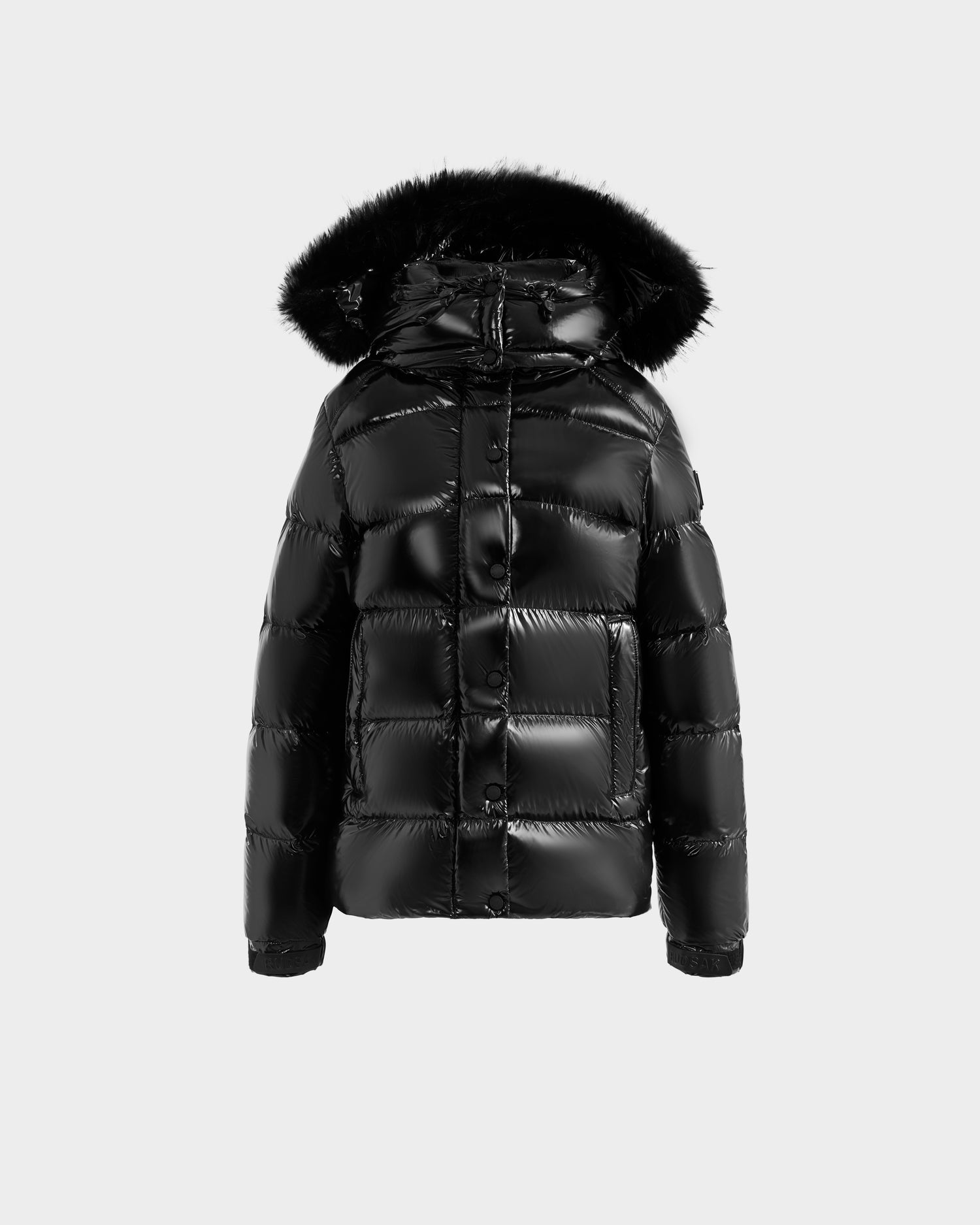 The Rudsak BREE S - L125583 Black is a women’s shiny black down puffer jacket with an ultra-gloss finish and a hood trimmed in black faux fur, shown against a plain light gray background.