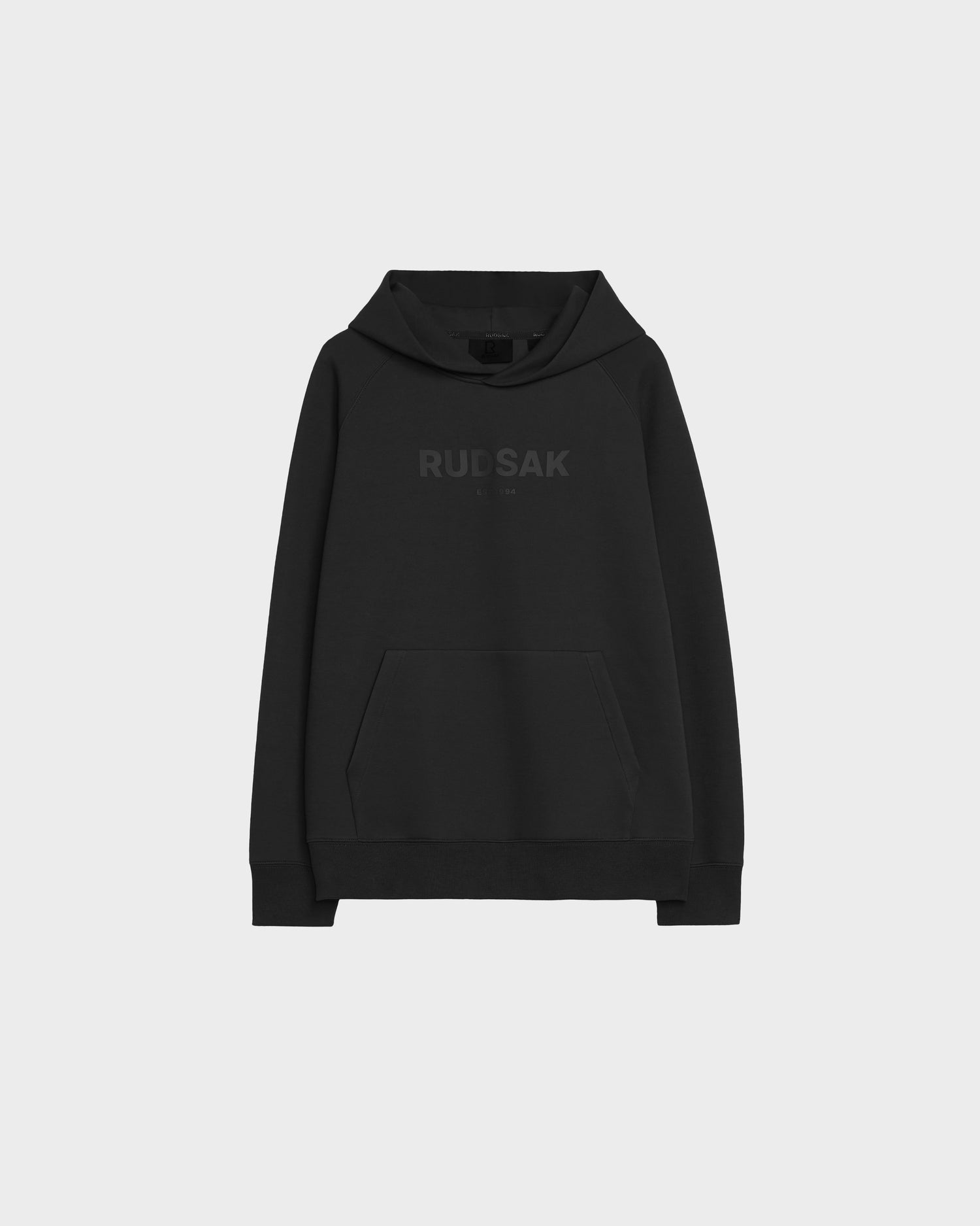 The BRIAR - 9525001 Black W by Rudsak is a unisex hoodie made from a premium cotton blend, with a front pocket and RUDSAK in dark letters on the chest, shown against a plain light gray background.
