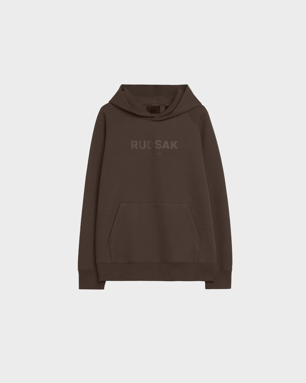 The Rudsak BRIAR - 9525001 Espresso M is a brown unisex hoodie made from a premium cotton blend, featuring a front kangaroo pocket and bold RUDSAK lettering across the chest, styled against a plain light gray background.