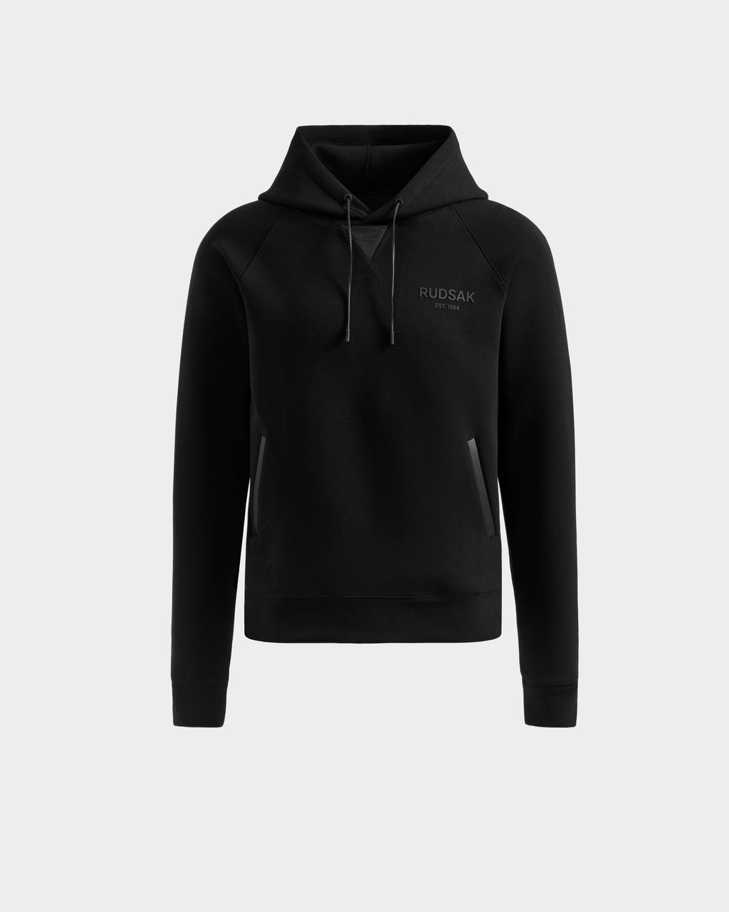 The Rudsak BROOKLYN - 6525593 black men’s hoodie features long sleeves, a front pocket, drawstrings, and the Rudsak logo on the upper left chest, shown against a plain light gray background.