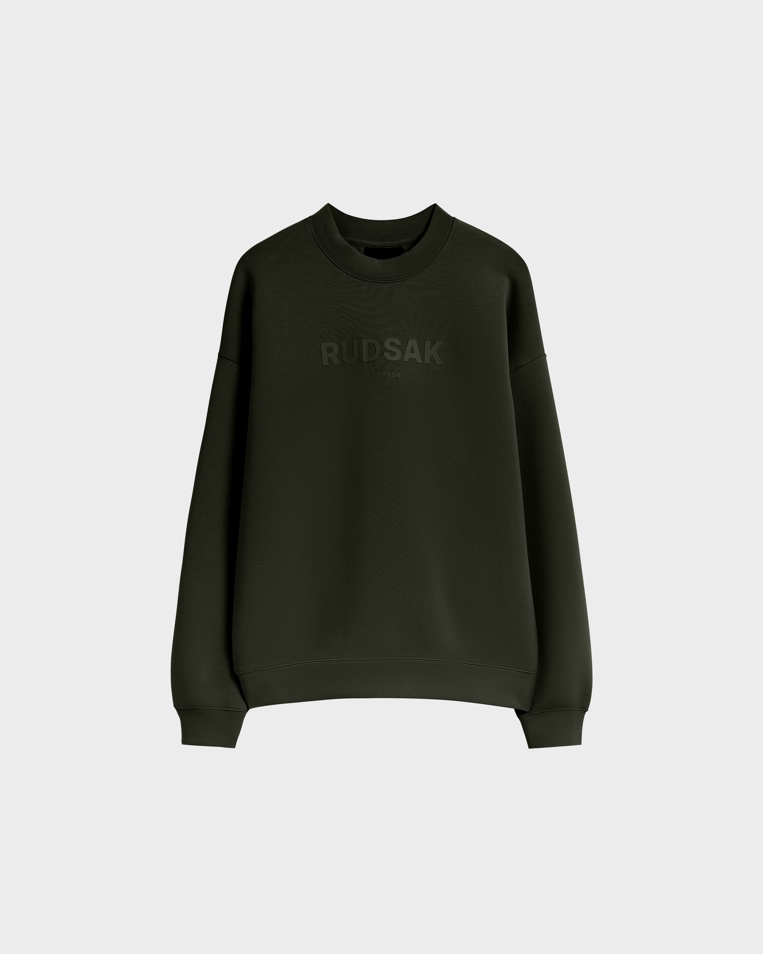 The Rudsak BRYN - 9524007 is a dark olive cotton crewneck sweatshirt with long sleeves and subtle chest branding, designed in genderless sizing, shown against a plain light gray background.