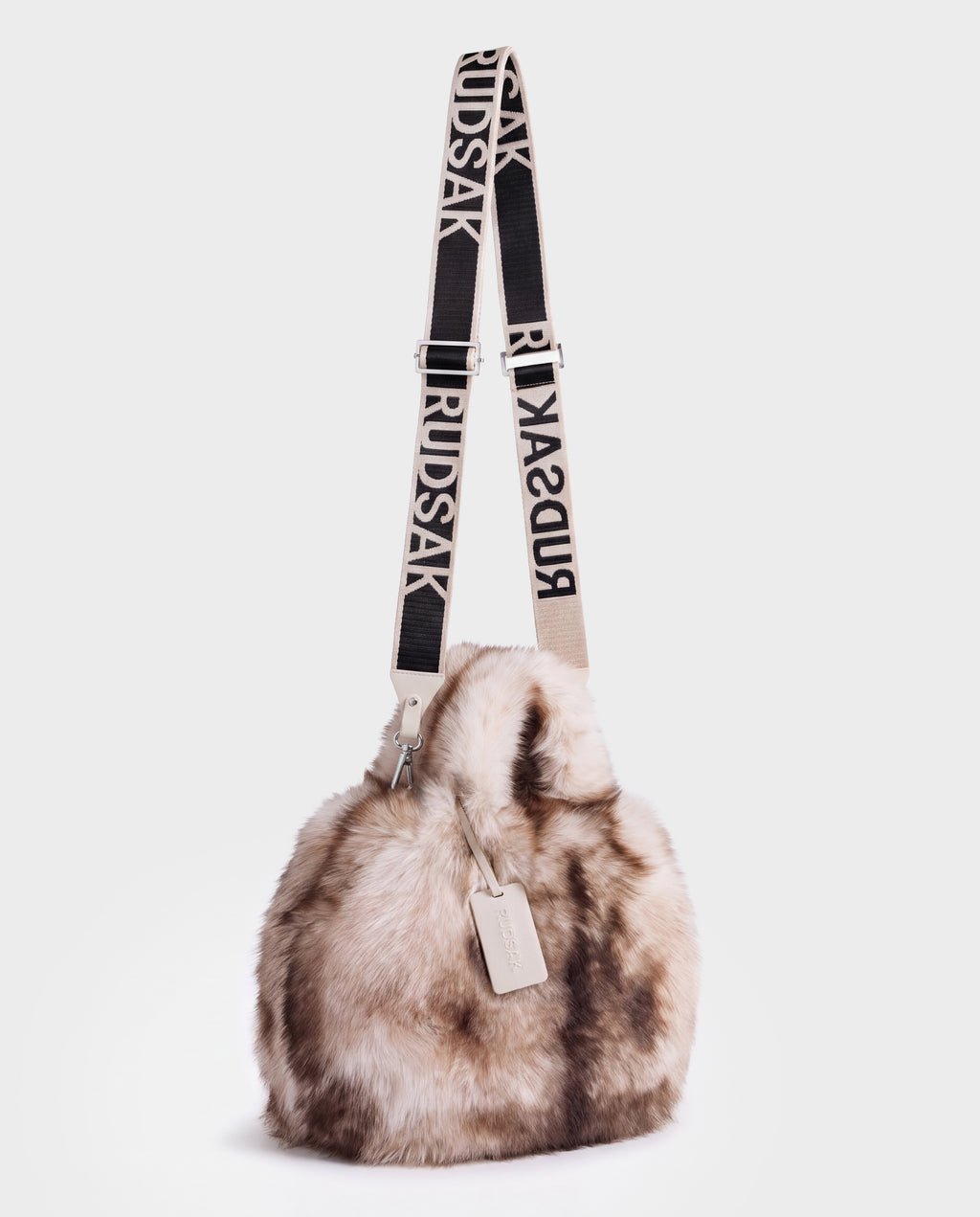 A plush, faux fur CABAS - 8325545 Mix Vanilla mini tote bucket bag with a long, adjustable shoulder strap featuring repeating text logos, perfect for layering over winter styles.