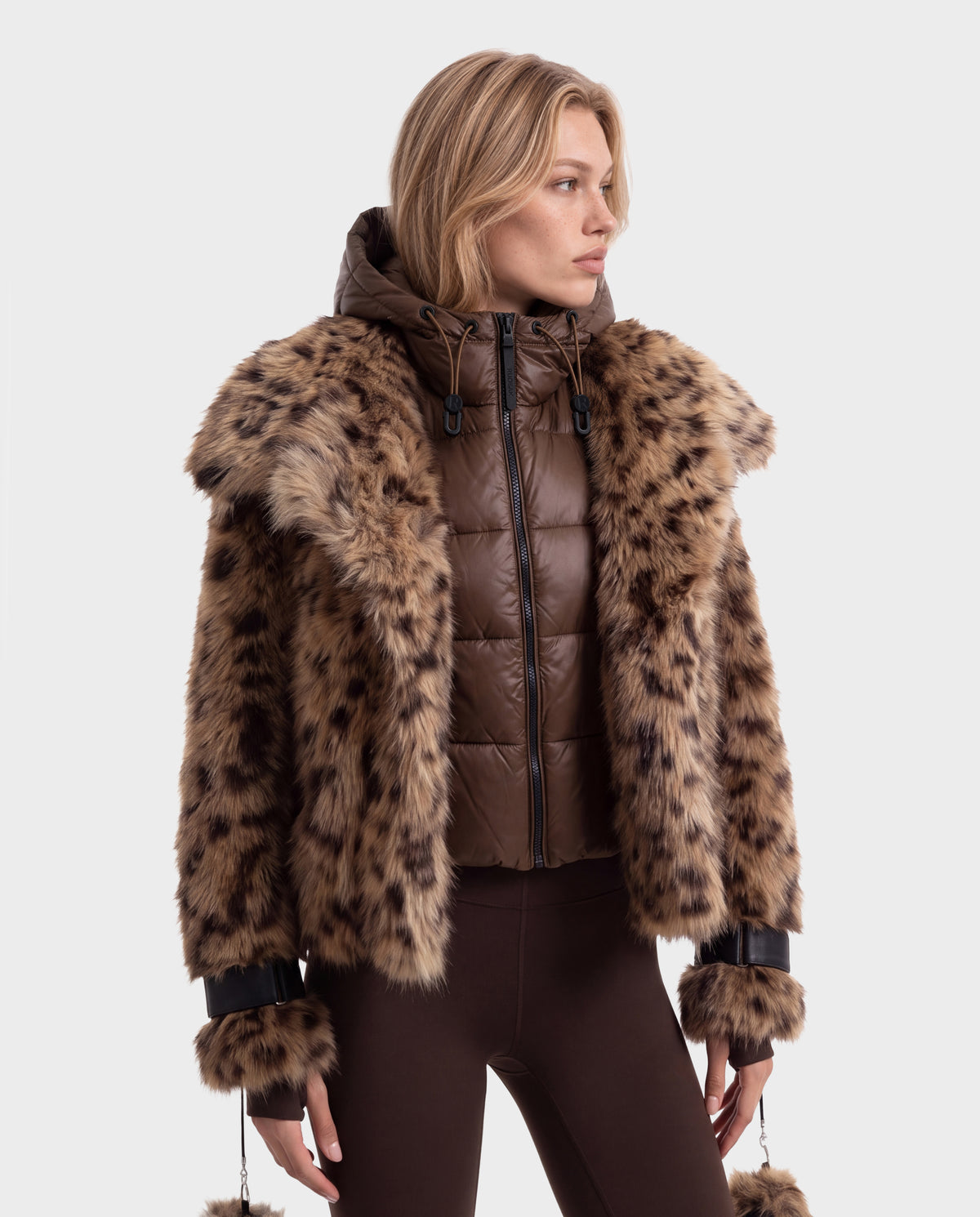 A person wearing a brown Rudsak CHLOE - 8125619 Leopard quilted zip-up winter jacket with a leopard-print faux fur collar and cuffs.