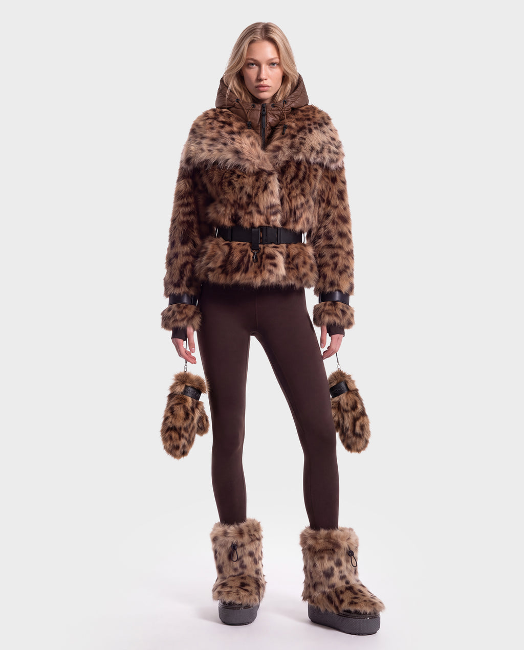 Model wearing a Rudsak CHLOE - 8125619 Leopard belted faux-fur jacket, brown leggings, leopard-print fur mittens, and matching platform snow boots for a complete winter wardrobe.