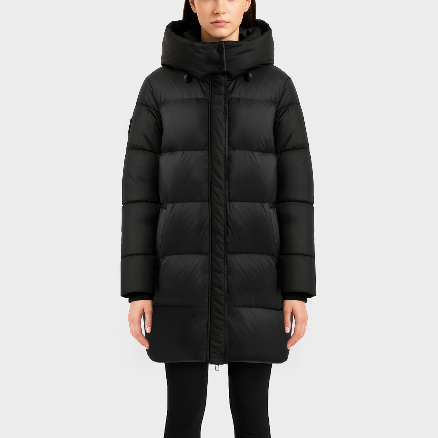 A person models the Rudsak OLIVIA - 4123509 Black long, hooded puffer coat, standing facing forward against a plain light background with arms relaxed at their sides.