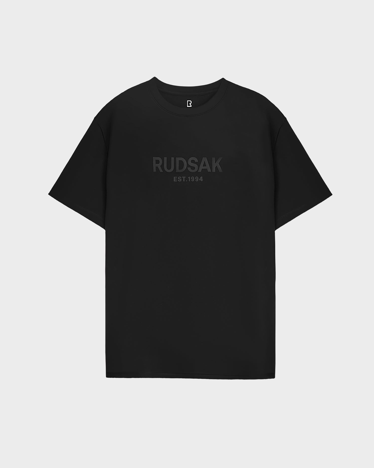 The CASEY - 6525037 Black by Rudsak is a men’s black short-sleeve T-shirt with RUDSAK EST.1994 in dark gray on the chest, shown against a white background.