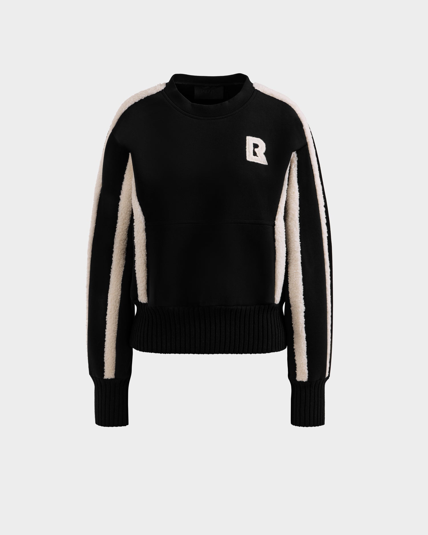 The Rudsak CHANA - 8525656 Black women’s crew neck sweatshirt features white vertical sleeve stripes and a white R patch on the left chest, offering après-ski chic style, shown on a plain light gray background.