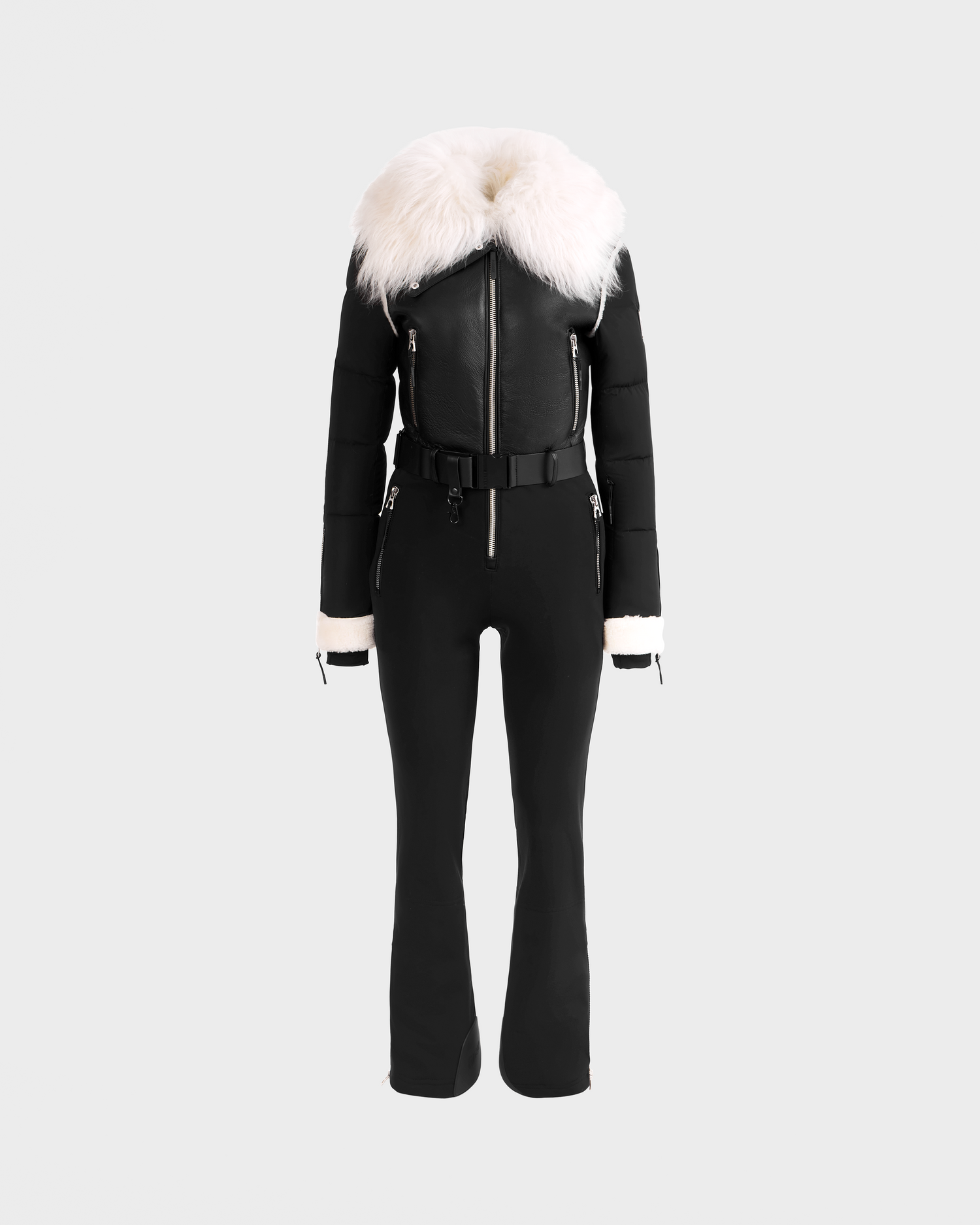 The Rudsak CHYNTIA - 8125611 Black: a black fitted jumpsuit with zip front, belted waist, white faux fur collar and cuffs, shown on a light gray background. Available for pre-order; ships by November 30th.