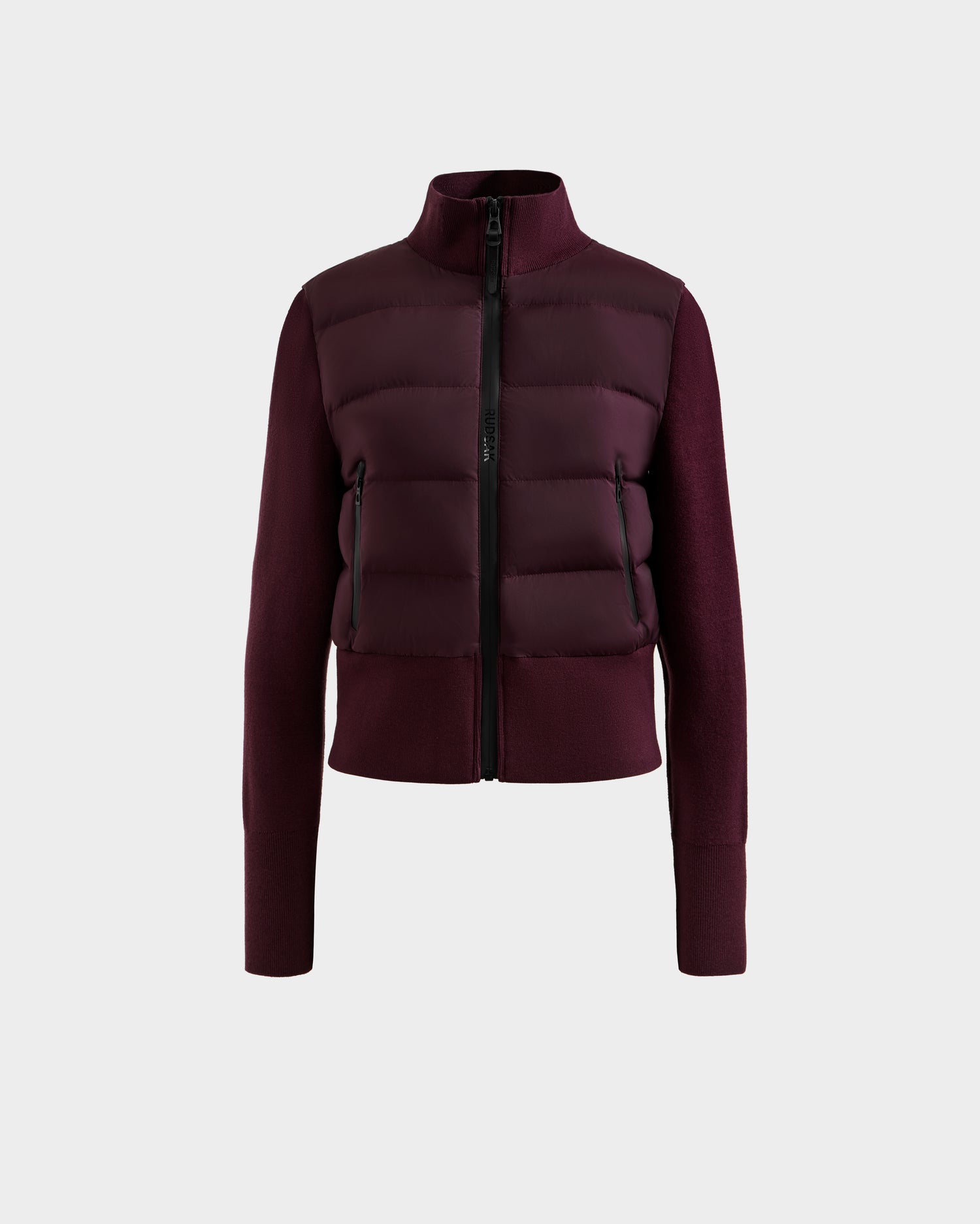 The Rudsak CLAREMONT - 8125502 Bordeaux is a women’s hybrid down jacket with a high collar, front zipper, fitted sleeves, and padded horizontal quilting. RDS-certified, it delivers lightweight warmth and a sleek, bulk-free look.