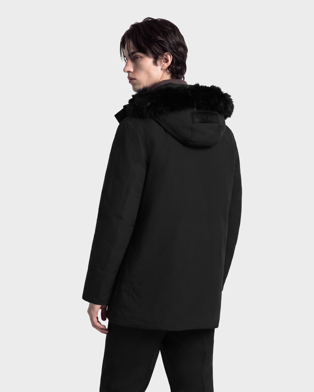 A man viewed from behind, wearing a black Rudsak EDWARD - 6126501 Black deep-winter parka with a faux fur trim.