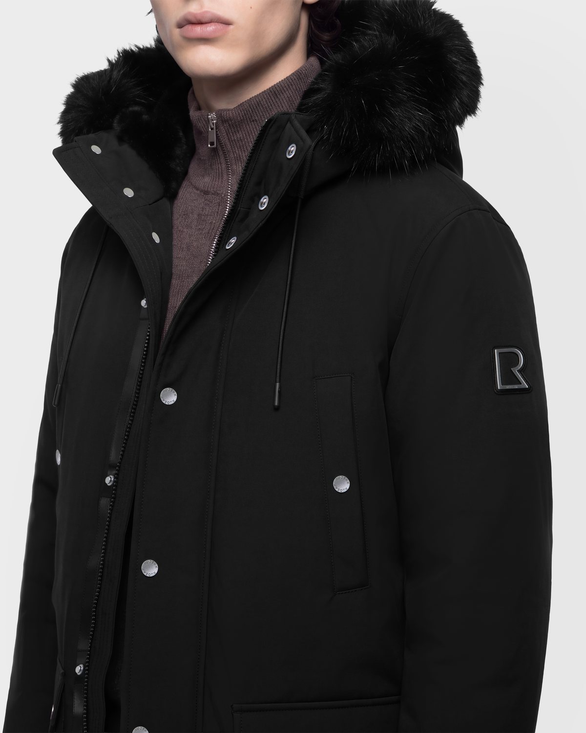 Black EDWARD - 6126501 Rudsak parka with a fur-trimmed hood and a metallic logo patch on the sleeve.