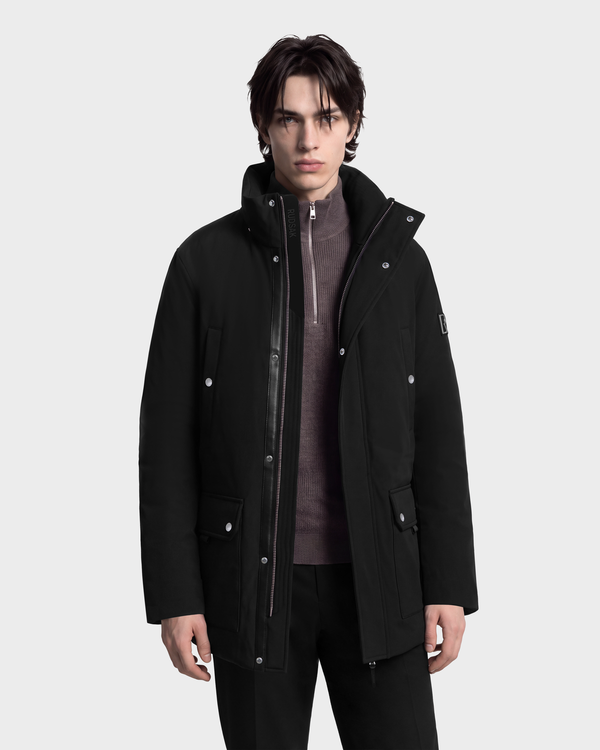 A person wearing an EDWARD - 6126501 Black parka with a zipper closure and a grey quarter-zip sweater underneath.