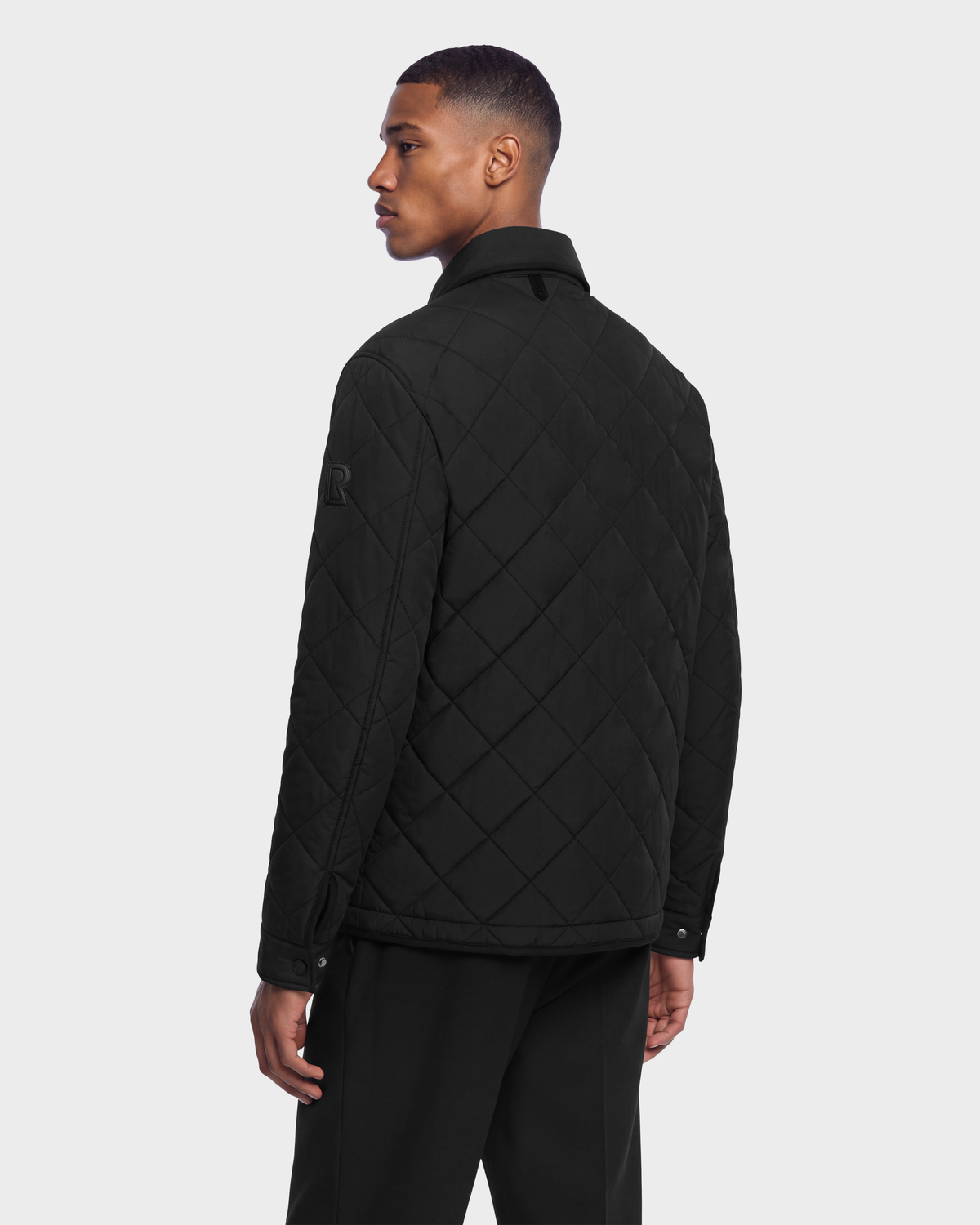 Man seen from behind wearing a black quilted HENDRIX - 6126721 Black jacket with a collar and snap-button cuffs.