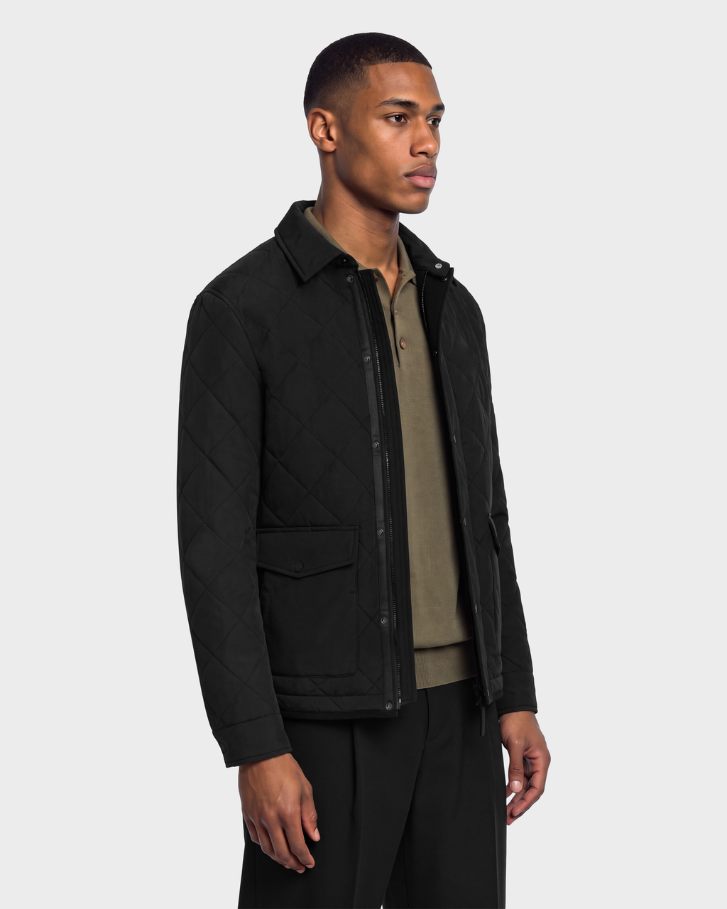 A man wearing a black Rudsak HENDRIX - 6126721 quilted jacket with a collared neckline over an olive green polo shirt.