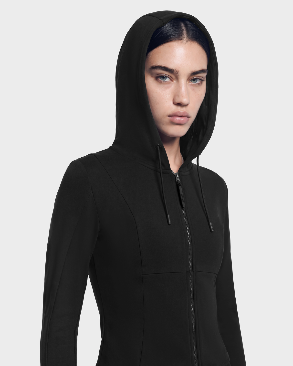 A person wearing a JUNIPER - 8526679 Black/Black fitted black zip-up hoodie with a cropped silhouette.