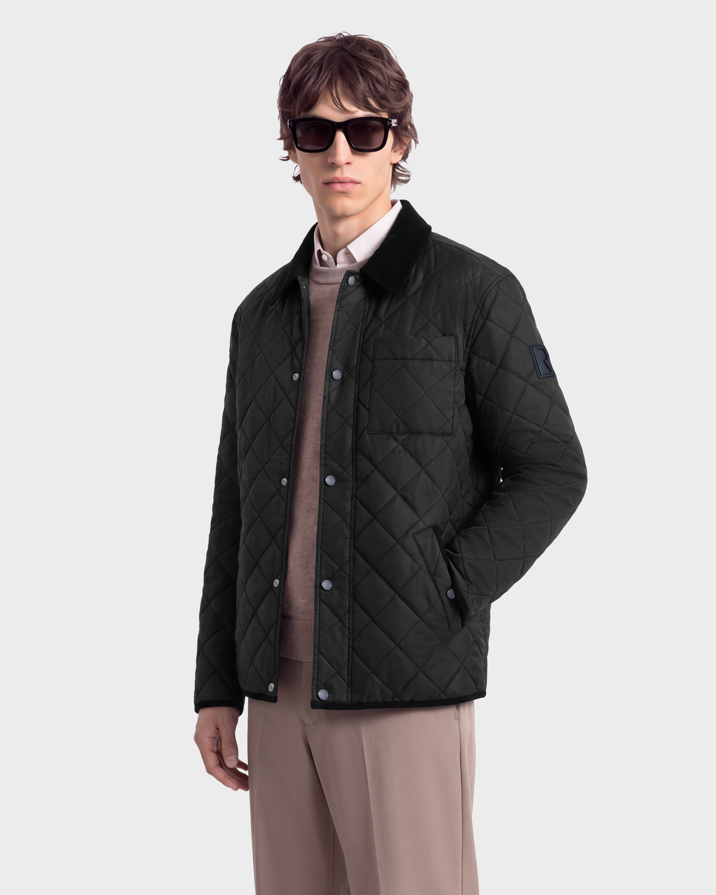 A man wearing a black Rudsak MONTY - 6126722 quilted snap-front jacket with a collared neck over a tan sweater and trousers.
