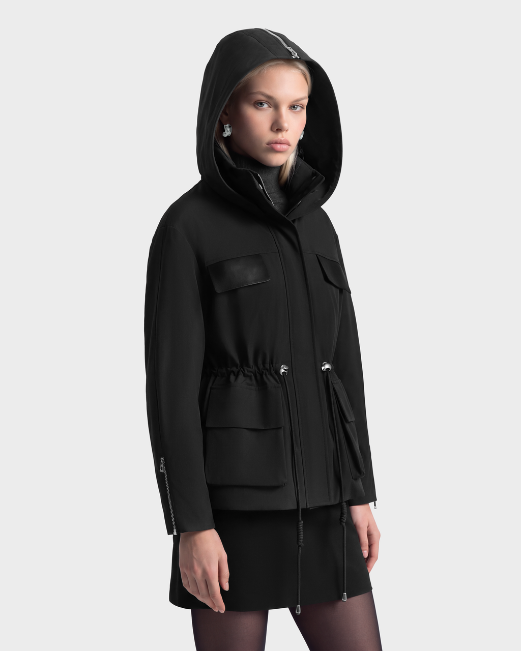 A model wearing a RUDSAK ROSALINDA - 8126523 Black insulated hooded jacket with a drawstring waist and multiple pockets.