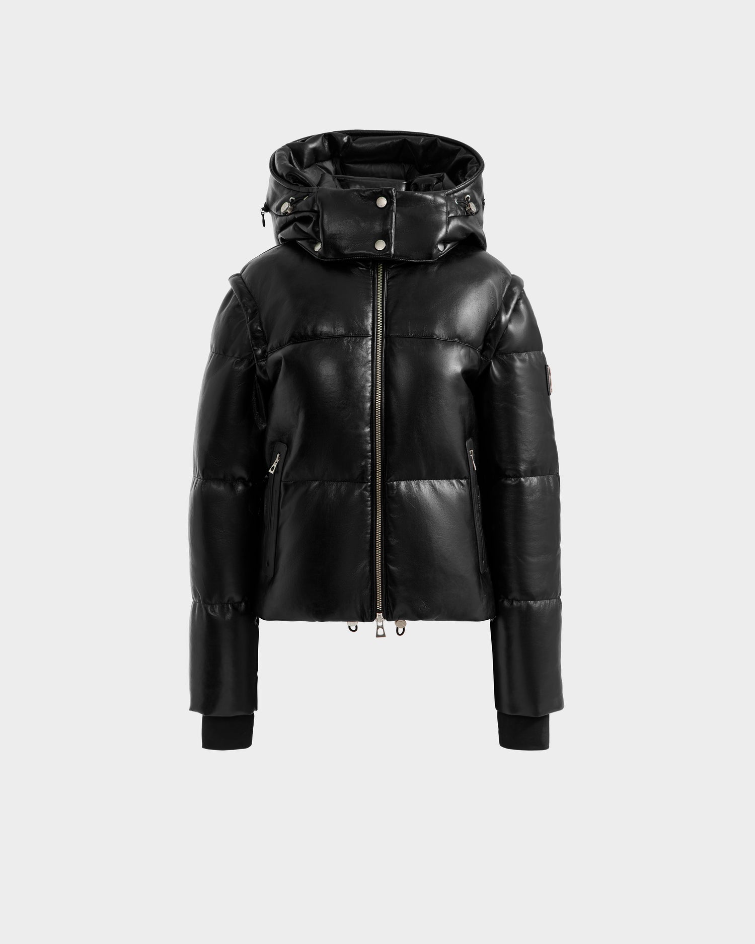 The DELILAH PX - L125537 Black by Rudsak, a women’s vegan-leather puffer jacket with a shiny finish, front zipper, high collar, attached hood, and ribbed-cuff long sleeves is shown on a plain light grey background.