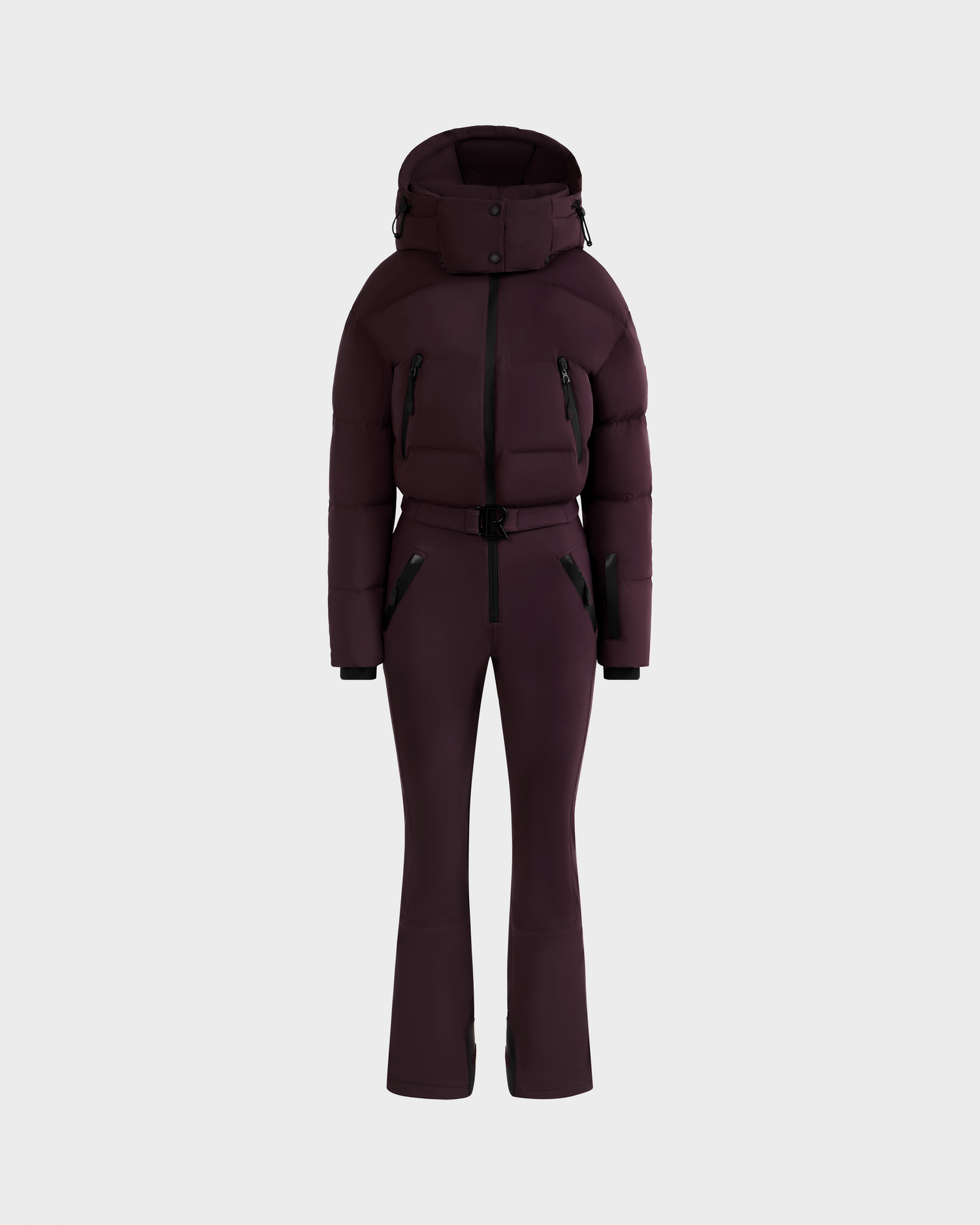 The DINARA - 8125600 Bordeaux by Rudsak is a dark plum women’s ski suit with a belted puffer jacket, hood, and fitted pants, shown on a light gray background and featuring RECCO rescue technology for enhanced safety.