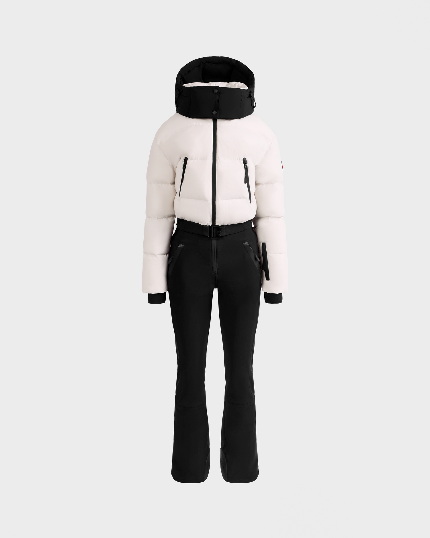 The Rudsak DINARA - 8125600 Vanilla women’s ski suit features a chic white puffer jacket with a hood and black accents, paired with fitted black ski pants—ideal for après-ski style on or off the slopes.
