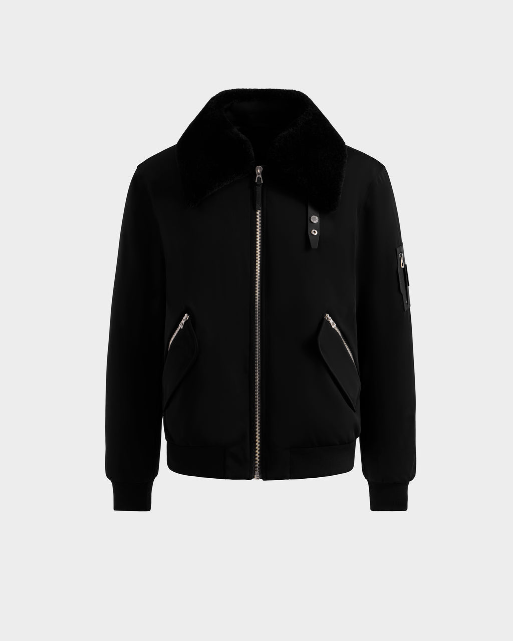 The Rudsak DYLAN - 6125593 Black men’s aviator bomber jacket features a removable faux fur collar, front zipper, two angled zippered pockets, ribbed cuffs and hem, and a zippered sleeve pocket, shown on a light gray background.
