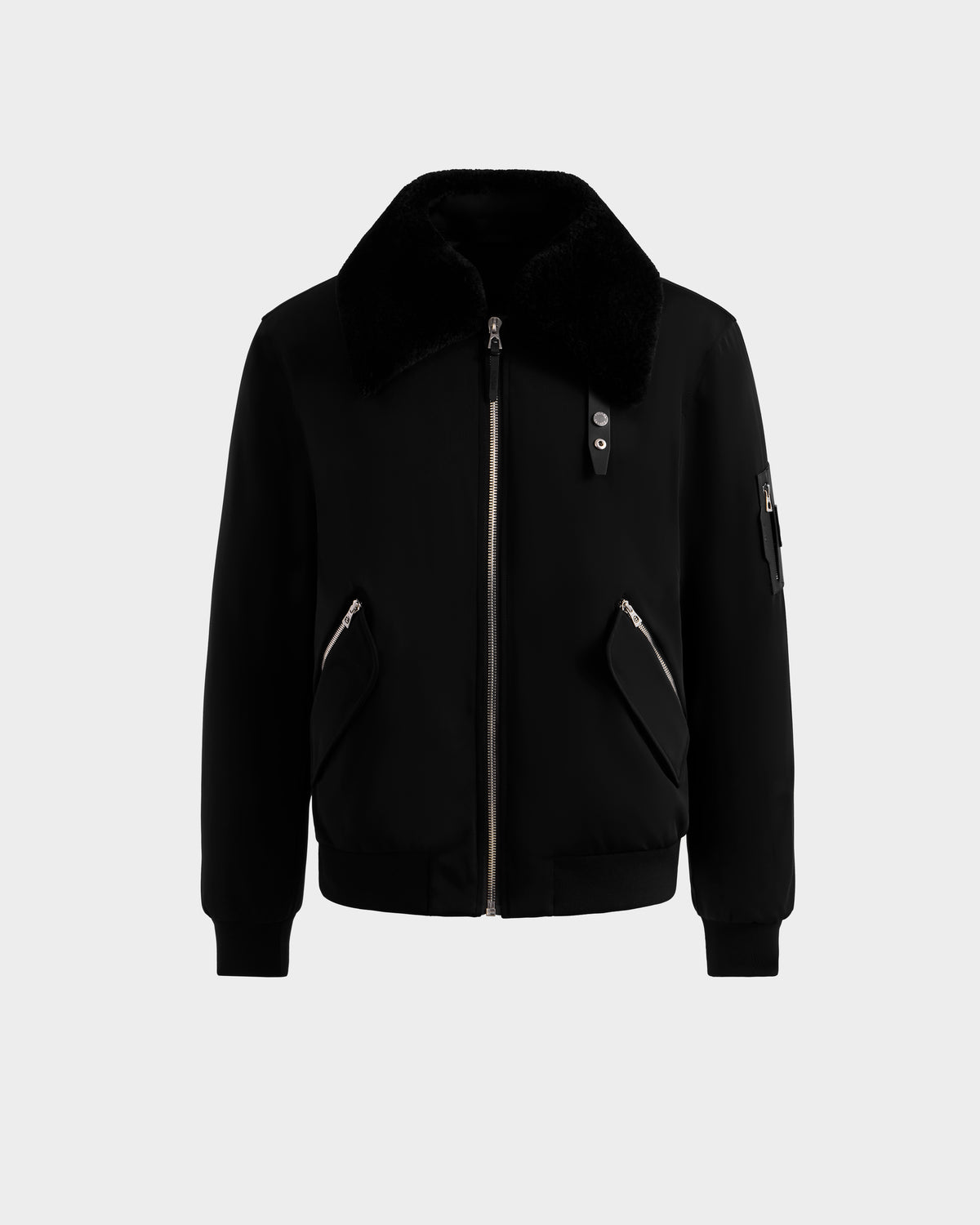 The Rudsak DYLAN - 6125593 Black men’s aviator bomber jacket features a removable faux fur collar, front zipper, two angled zippered pockets, ribbed cuffs and hem, and a zippered sleeve pocket, shown on a light gray background.