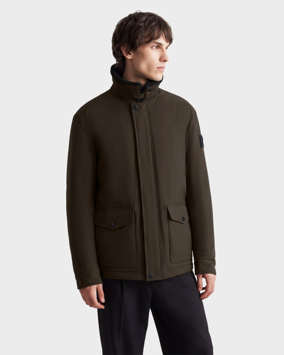 A man wears an ANTOINE - 6126506 Olive jacket in dark olive with a high collar, snap-button placket, and two large front flap pockets.