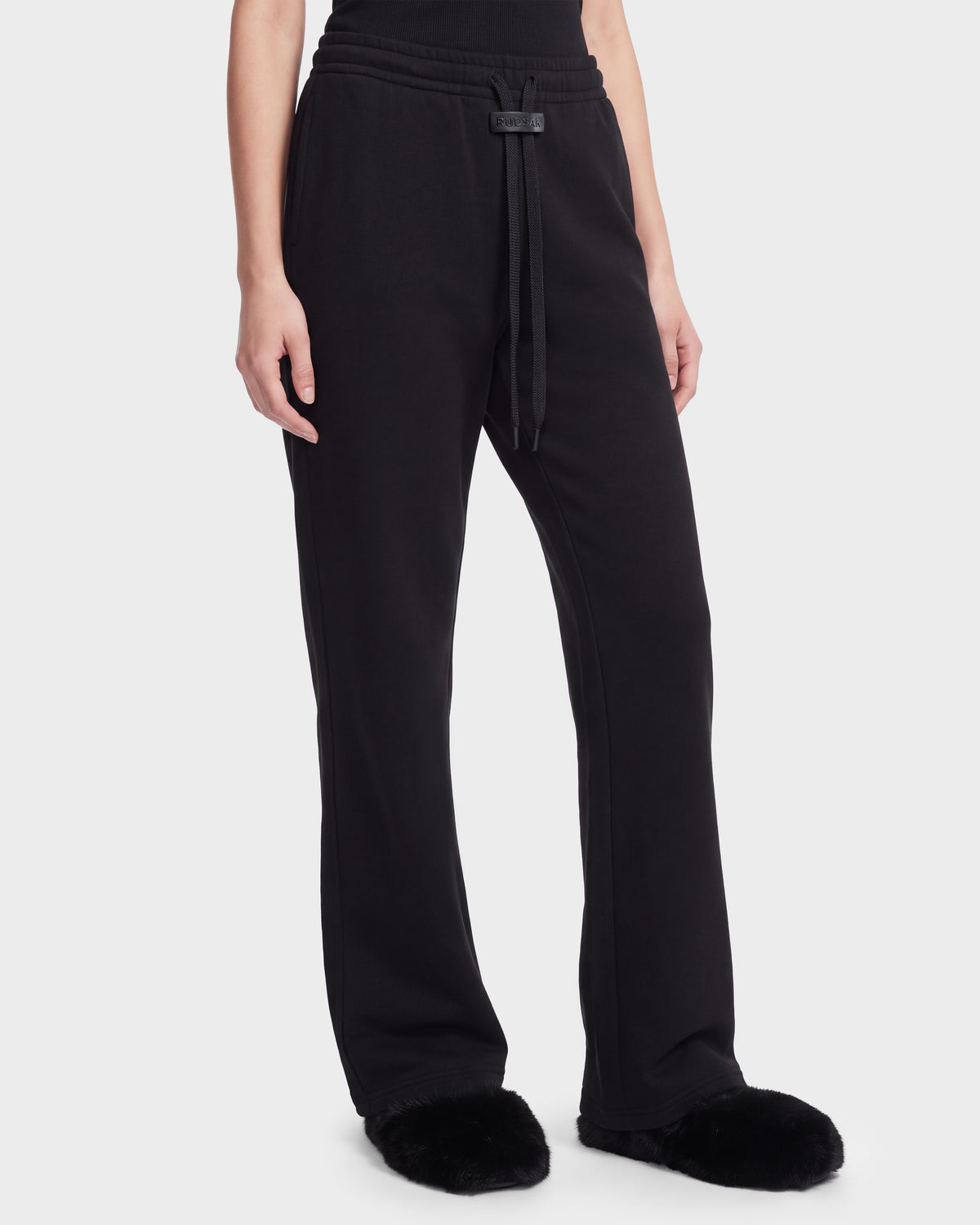 Rudsak ANGEL - 8526725 Black contemporary stretch cotton sweatpants with a drawstring waist, paired with fluffy black slippers for a refined off-duty look.