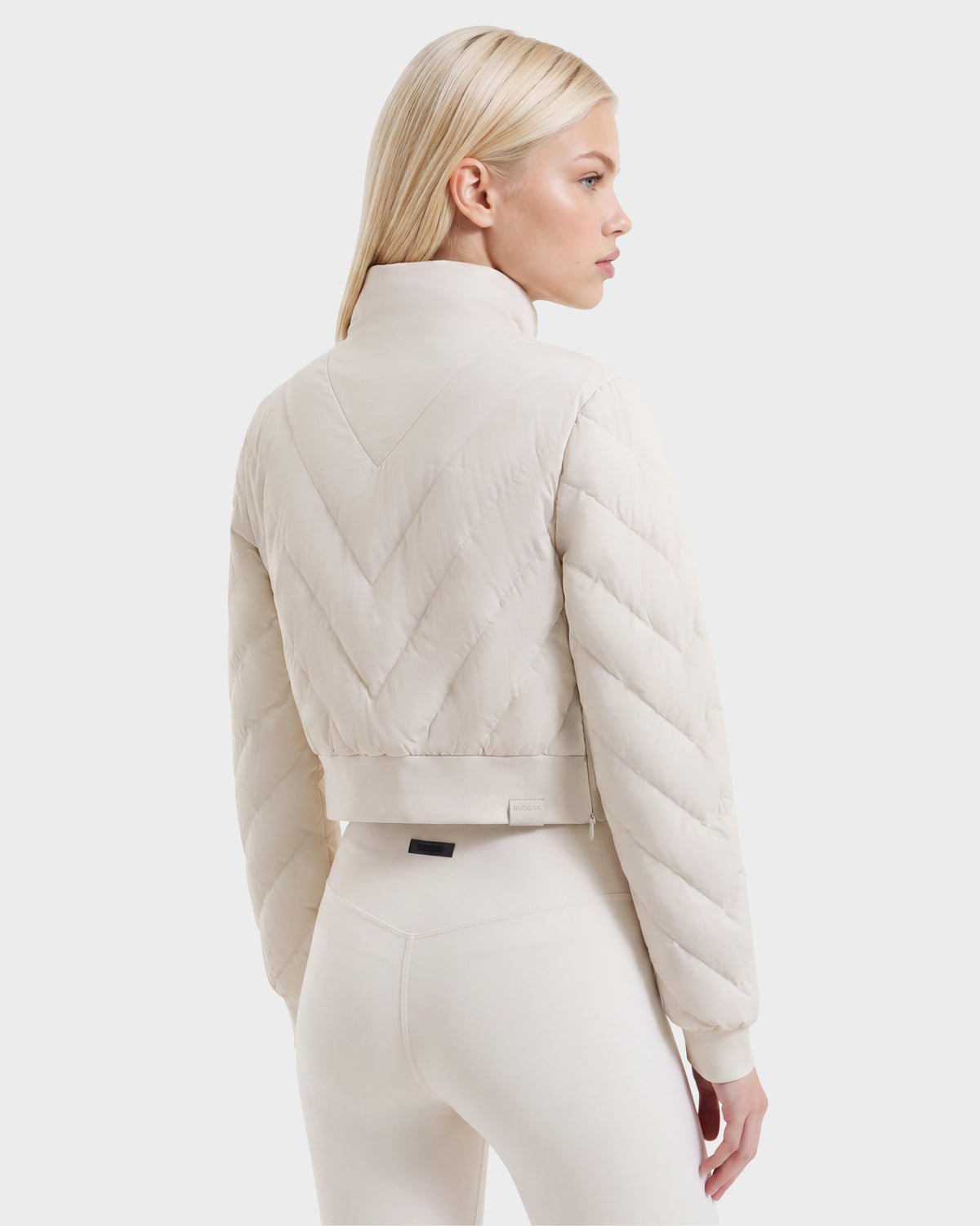 A woman wearing a vanilla-colored KATYA - 8526531 cropped down sweatshirt featuring chevron-patterned quilting.