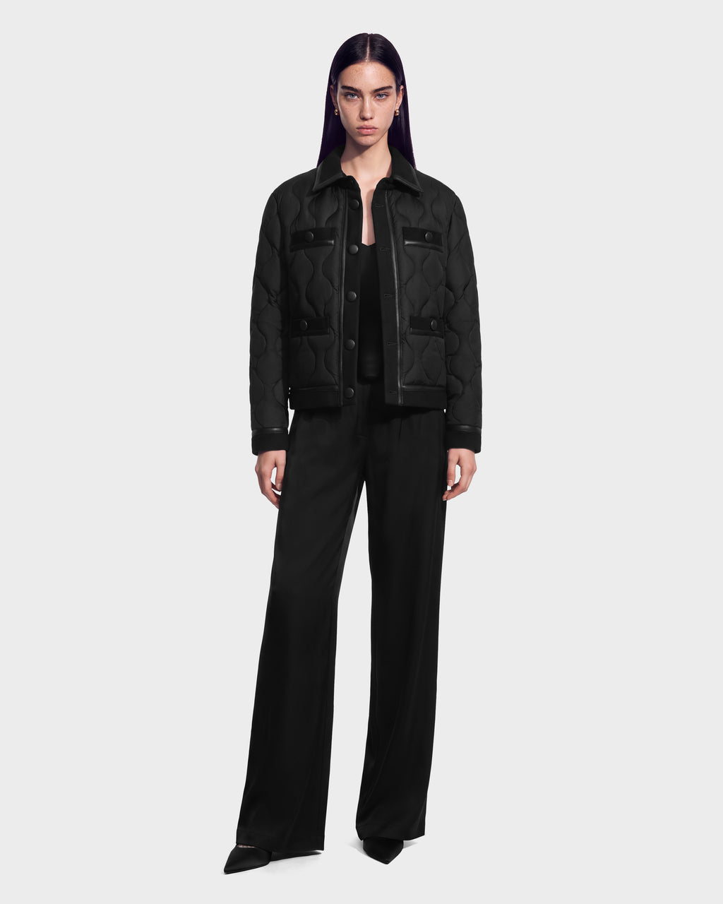 A model wearing a black JOLIE - 8125036 quilted down jacket with leather accents and wide-leg trousers.