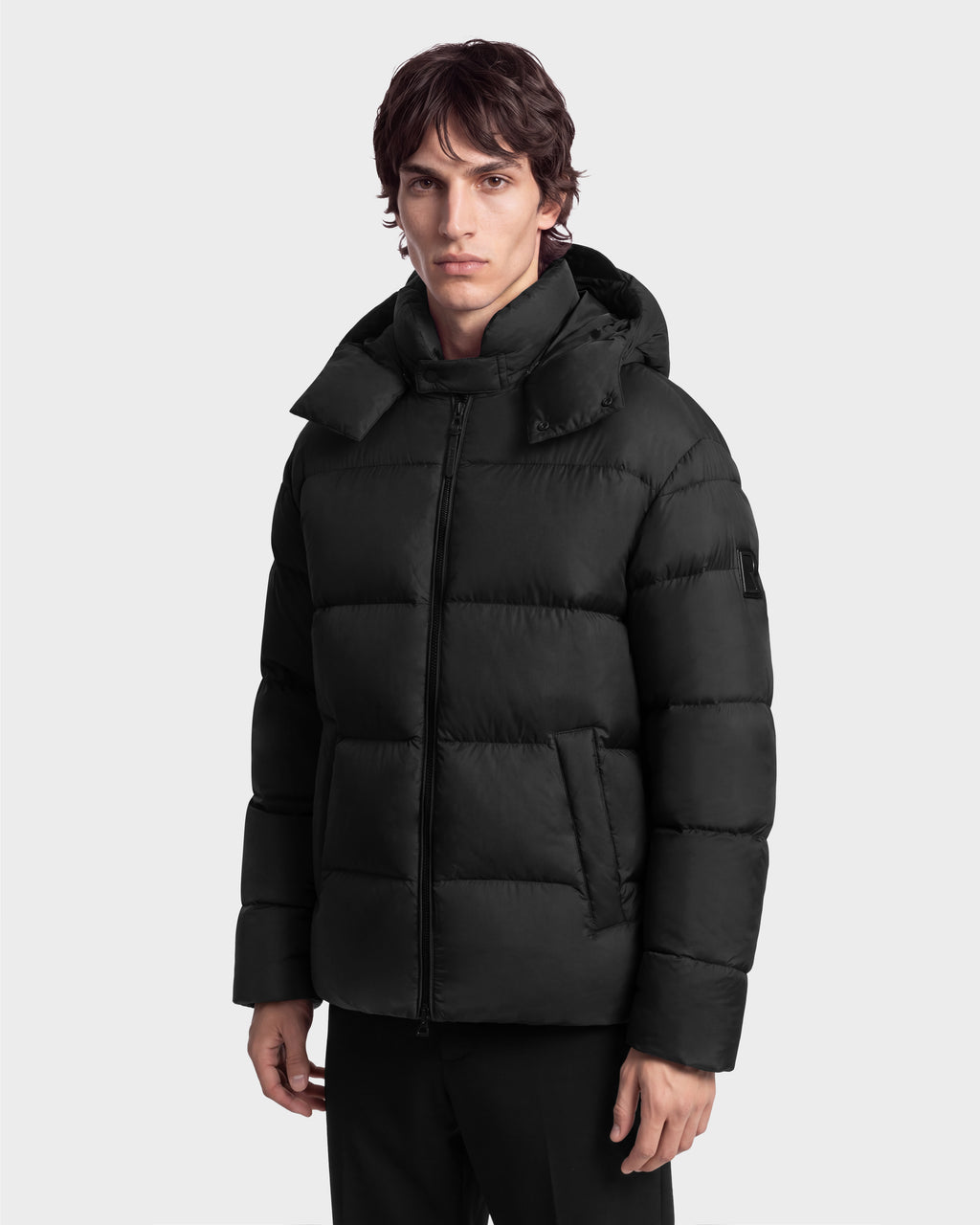 A person wearing a black Rudsak JASON - 6126803 Black hooded puffer jacket with a front zipper.