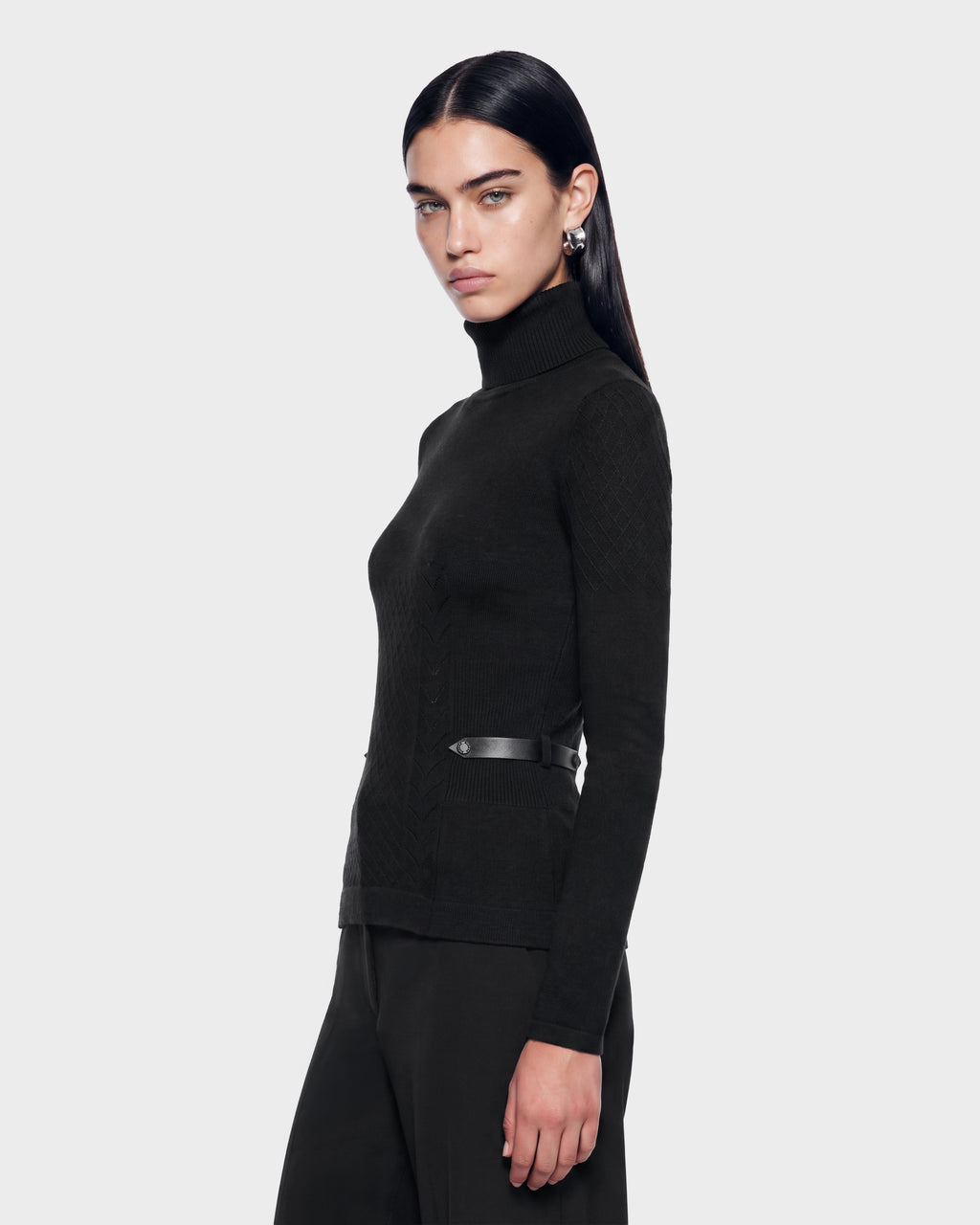 A woman wearing the Rudsak LAURA - 8524596 Black cashmere turtleneck sweater, featuring a thin waist belt and textured vegan leather side trim.