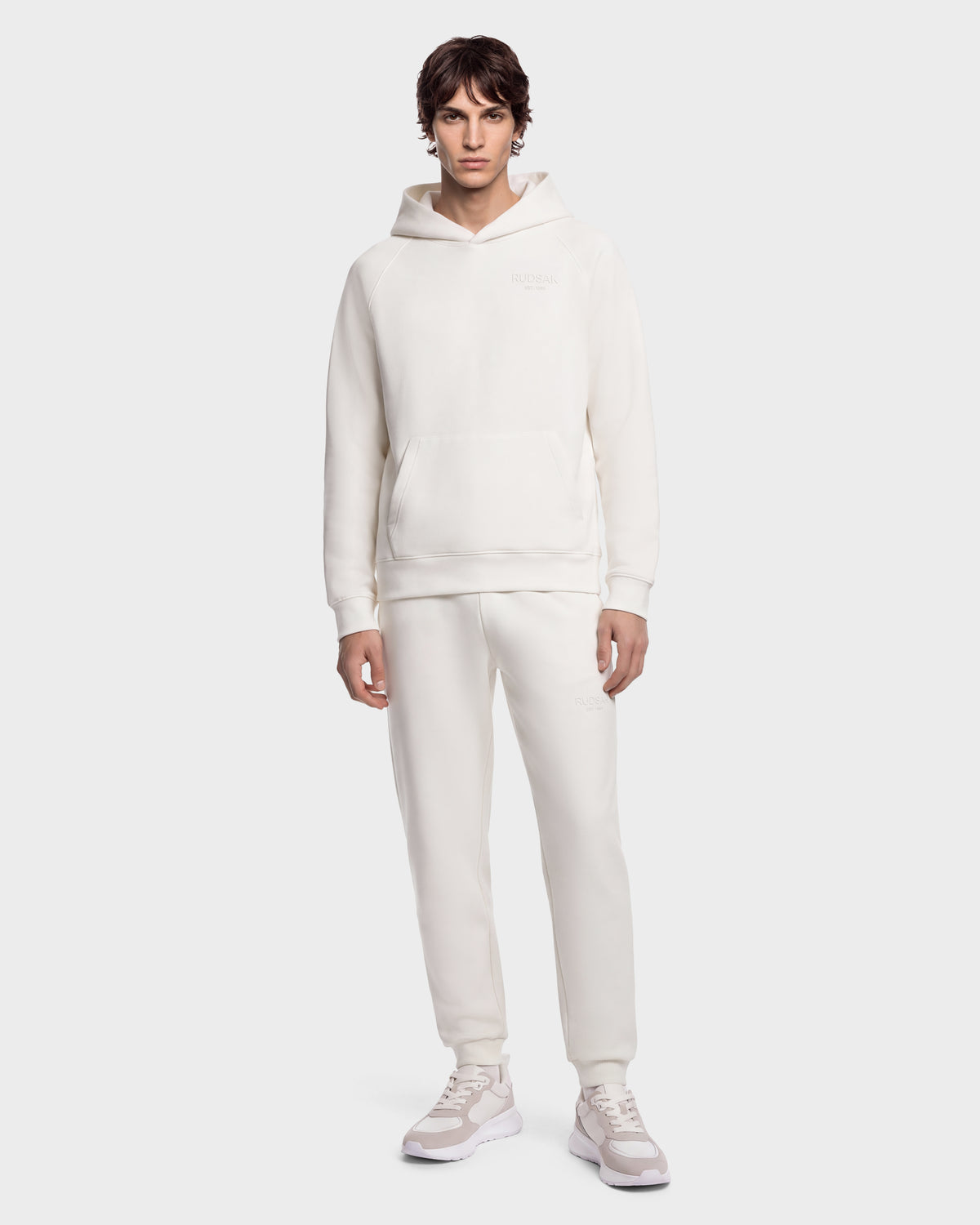 A person wears the BRIAR - 9525001 Vanilla M matching cream-colored hooded sweatshirt and sweatpants with white sneakers.