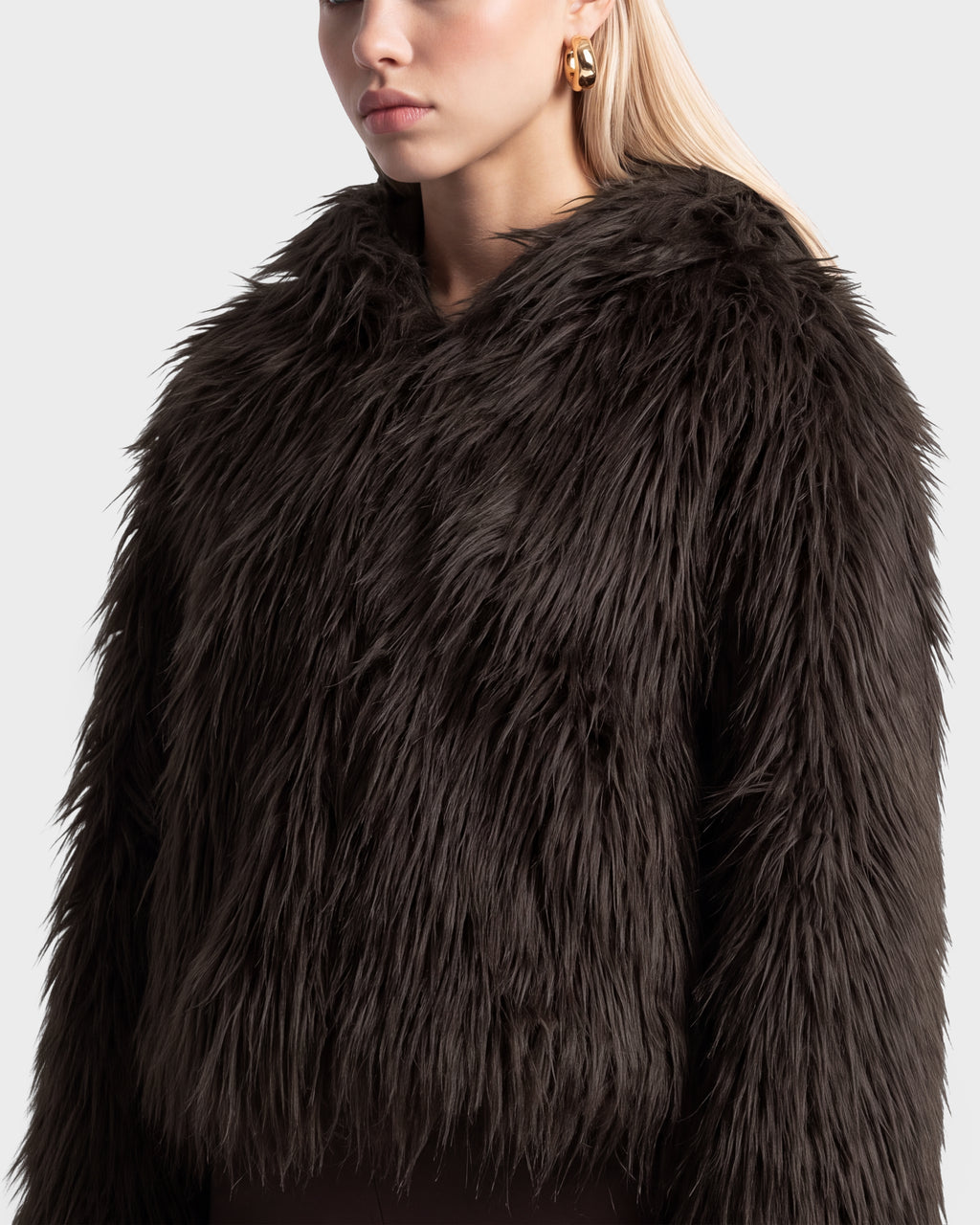 A person wearing the RUDSAK ELLISON - 8525678 Espresso dark brown faux fur hoodie with an oversized hood.