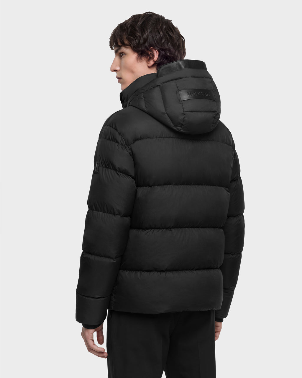 A person viewed from the back wearing a black Rudsak JASON - 6126803 Black quilted puffer jacket with a hood.
