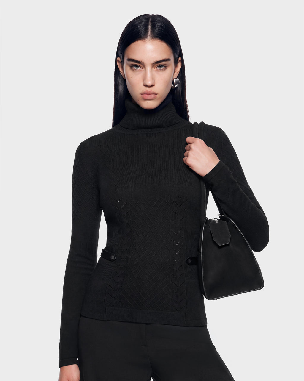 A person wearing a black cashmere turtleneck sweater with a diamond-patterned texture, carrying a LAURA - 8524596 Black shoulder bag with vegan leather trim.
