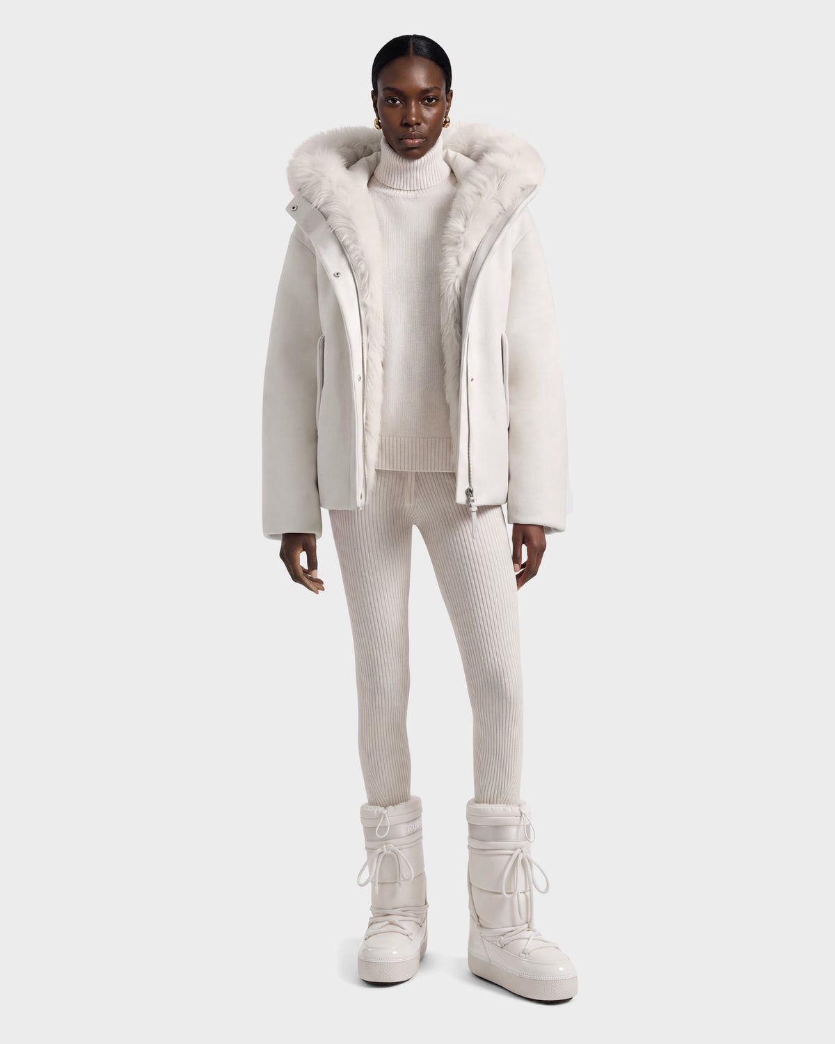 A model wears a HAZEL - 8126981 Vanilla wool-blend winter jacket with a detachable faux-fur hood, a matching turtleneck sweater, ribbed leggings, and lace-up snow boots.