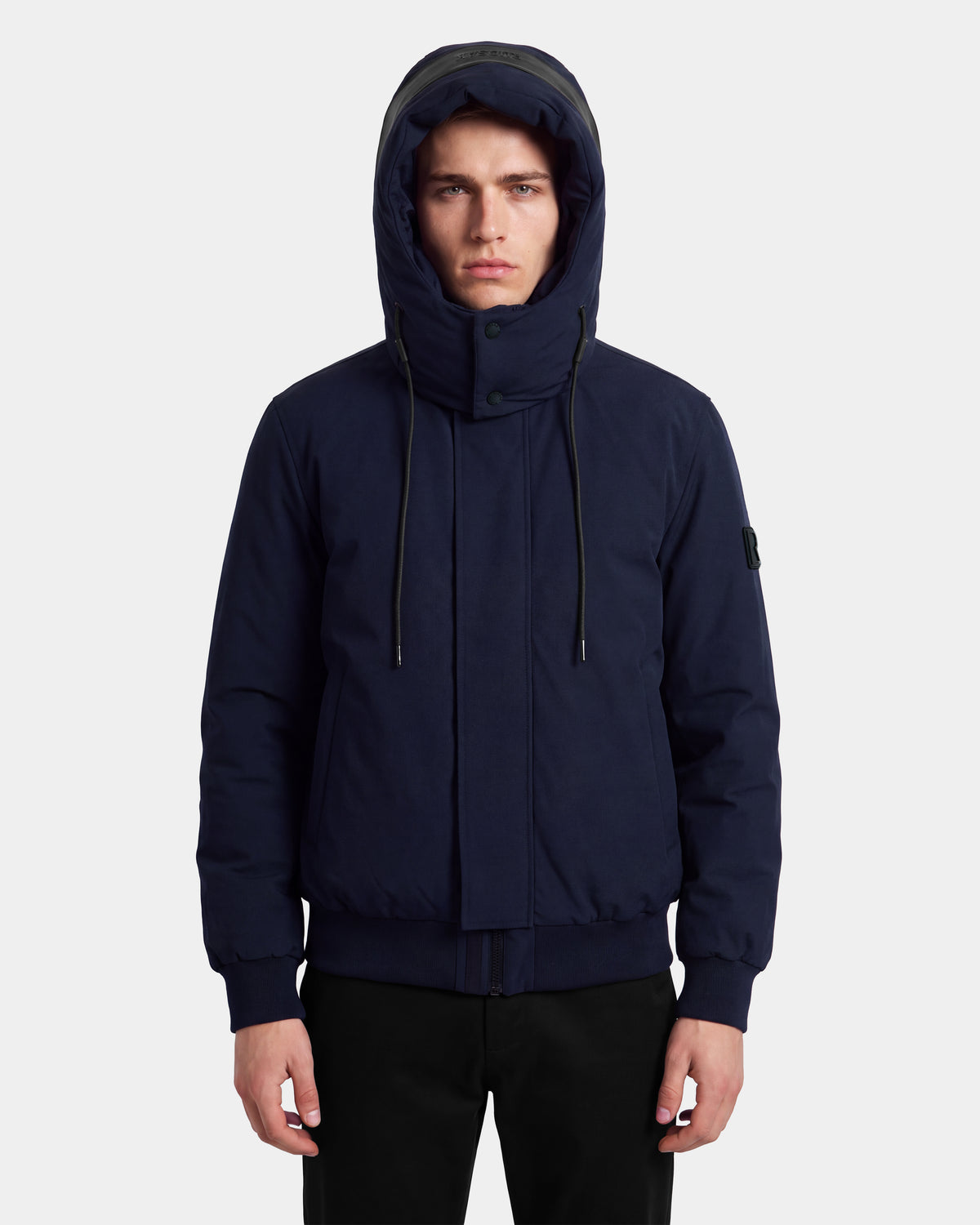 A person wearing the Rudsak WILL - 6126561 Navy hooded winter coat stands facing forward with hands by their sides. The jacket, filled with RDS-certified down, features a high collar, drawstrings, and front pockets. The background is plain white.