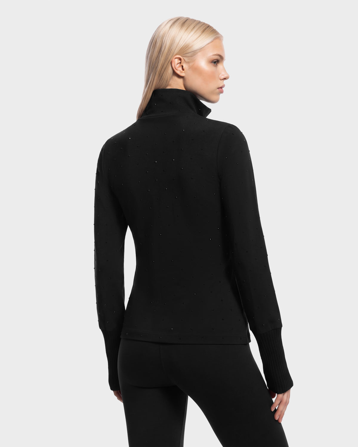 Back view of the Rudsak NEVA - 8526524 Black, a person wearing a black long-sleeve mock-neck top with small scattered embellishments and ribbed cuffs.
