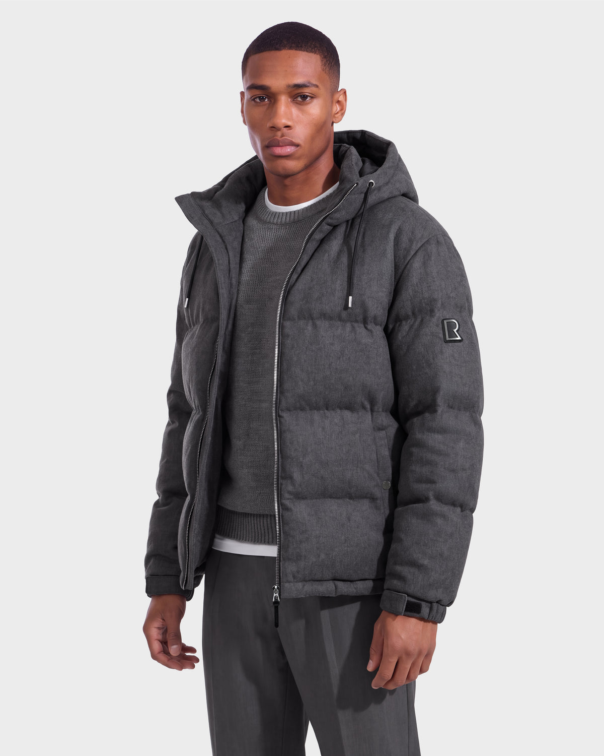 A man wearing the Rudsak STERLING W - 6126760 Heather Charcoal puffer jacket stands against a plain light background, looking at the camera.